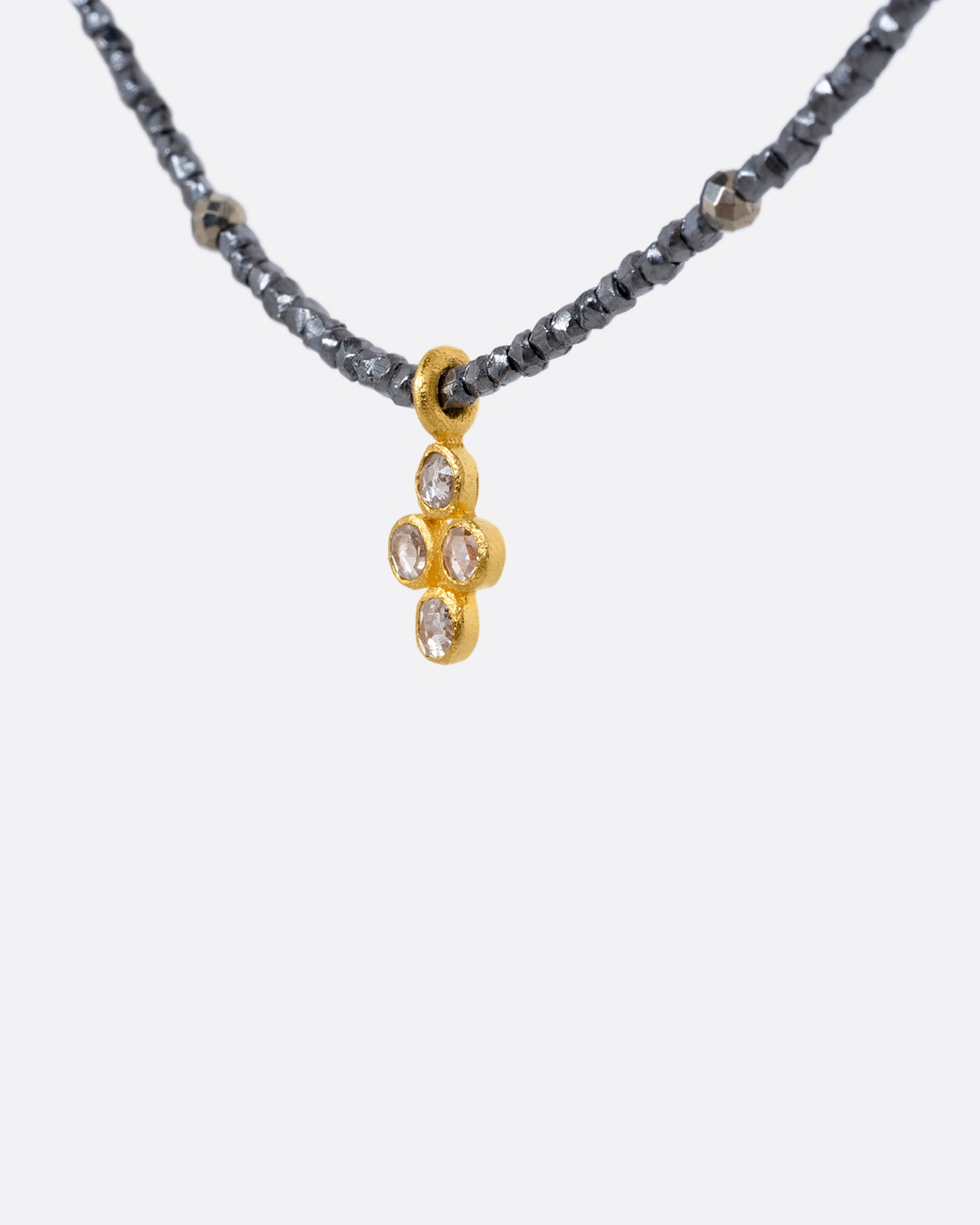 A pyrite bead necklace with a diamond quartet charm at the center. Shown from the side.