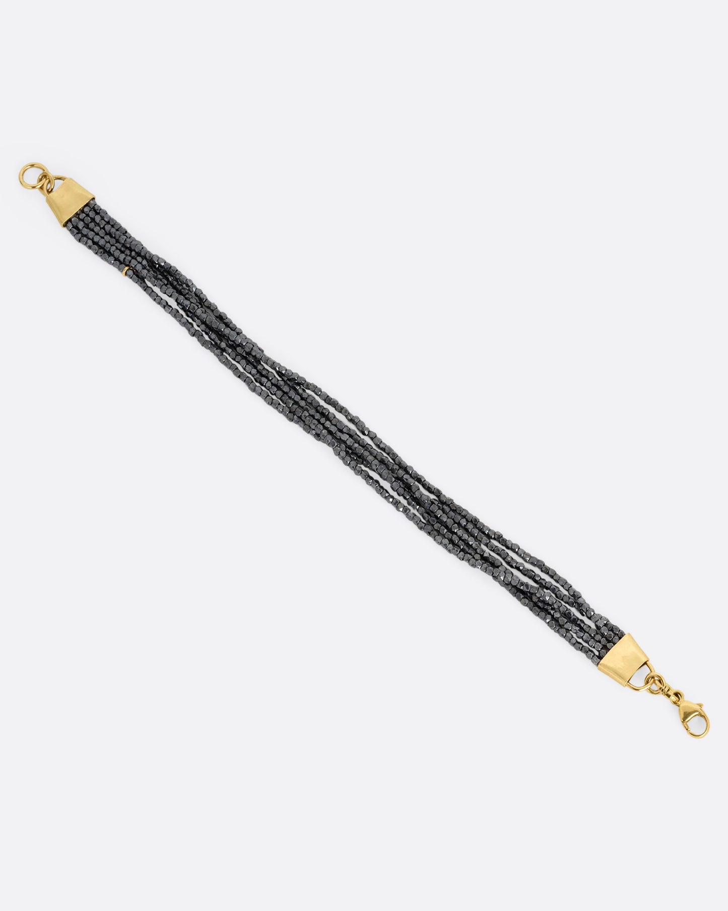 A bracelet with five strands of oxidized silver beads converging at yellow gold capped ends with a lobster clasp. Shown open from the top.