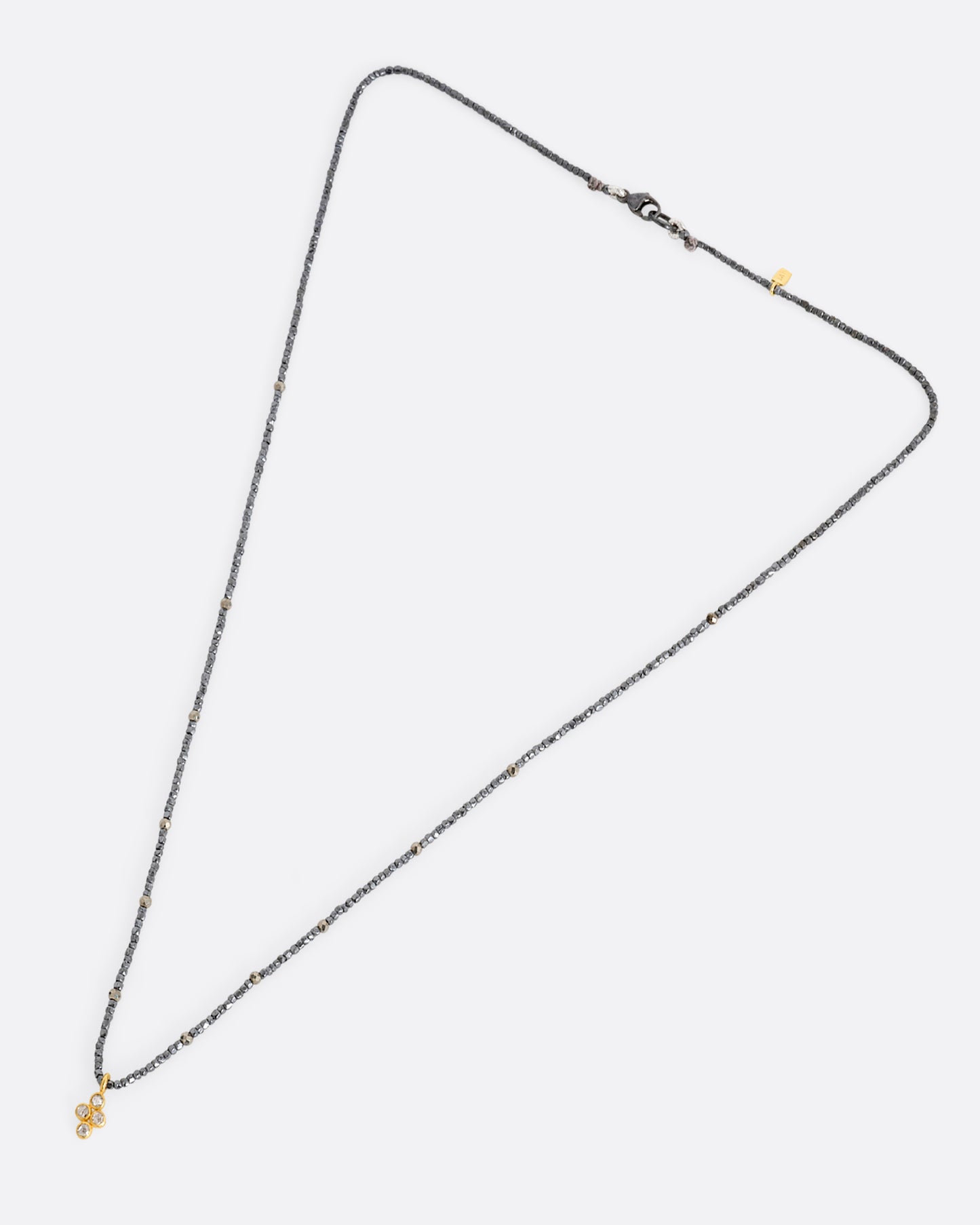 A pyrite bead necklace with a diamond quartet charm at the center. Shown lying flat from the front.