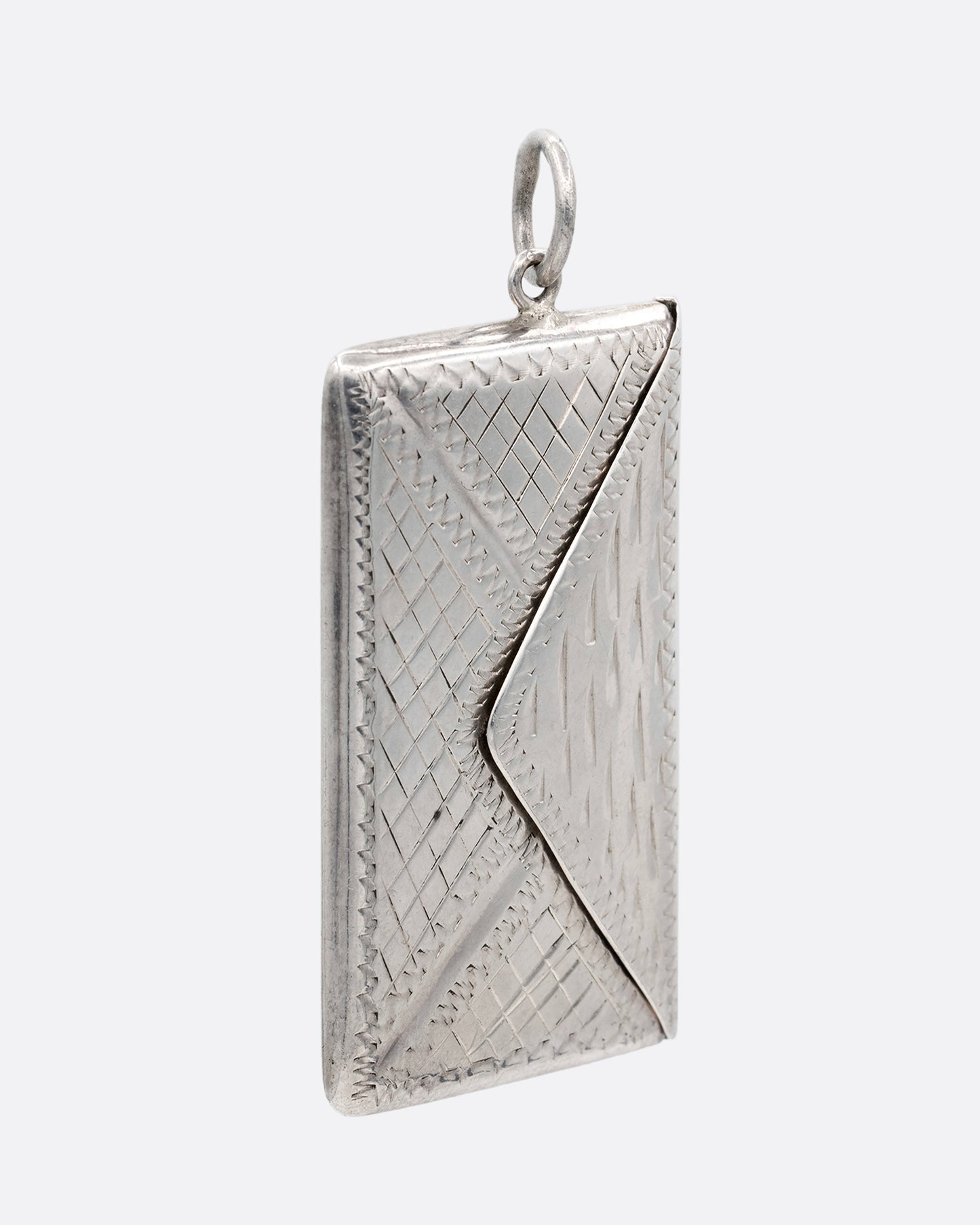 A silver textured envelope locket. Shown from the side.