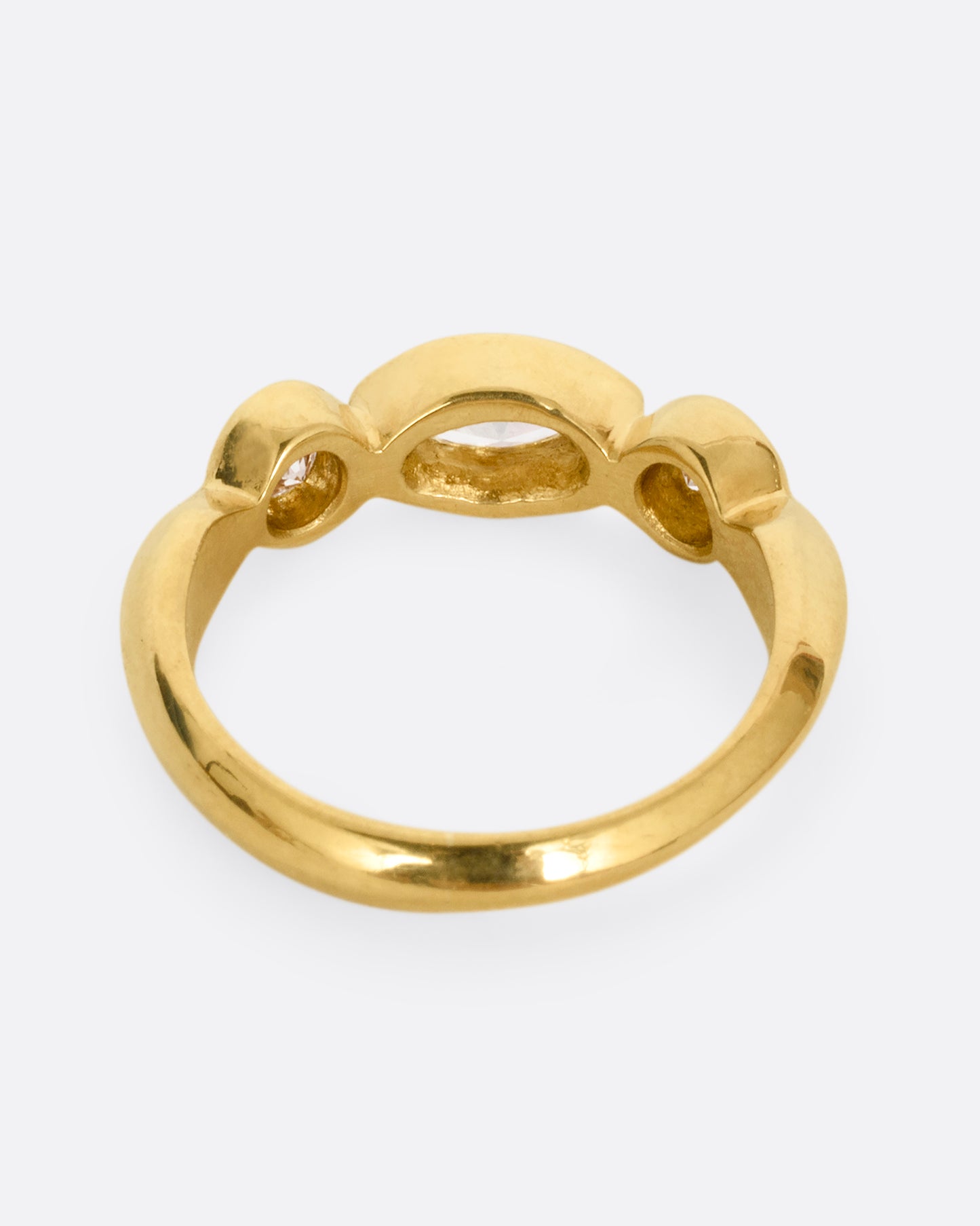 A yellow gold ring with three diamonds shown from the back.
