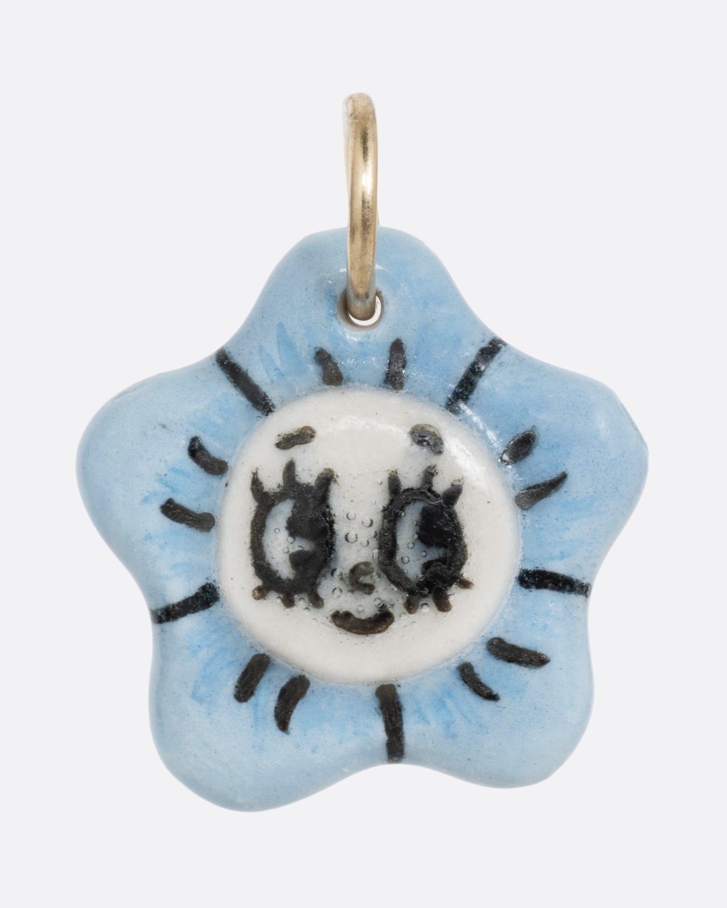 A blue flower porcelain flower charm with a face at the center. Shown from the front.