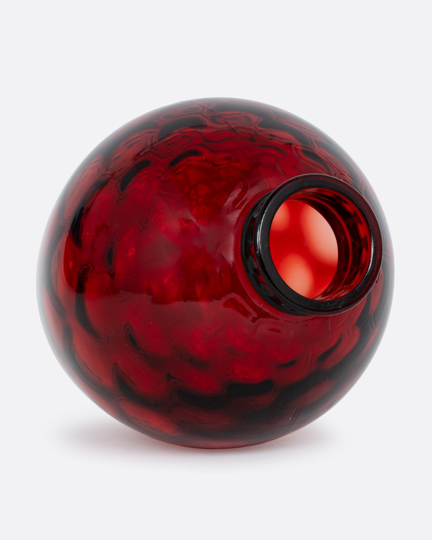 A red glass vase with a smooth exterior and honeycomb texture interior. Shown lying on its side from the top.