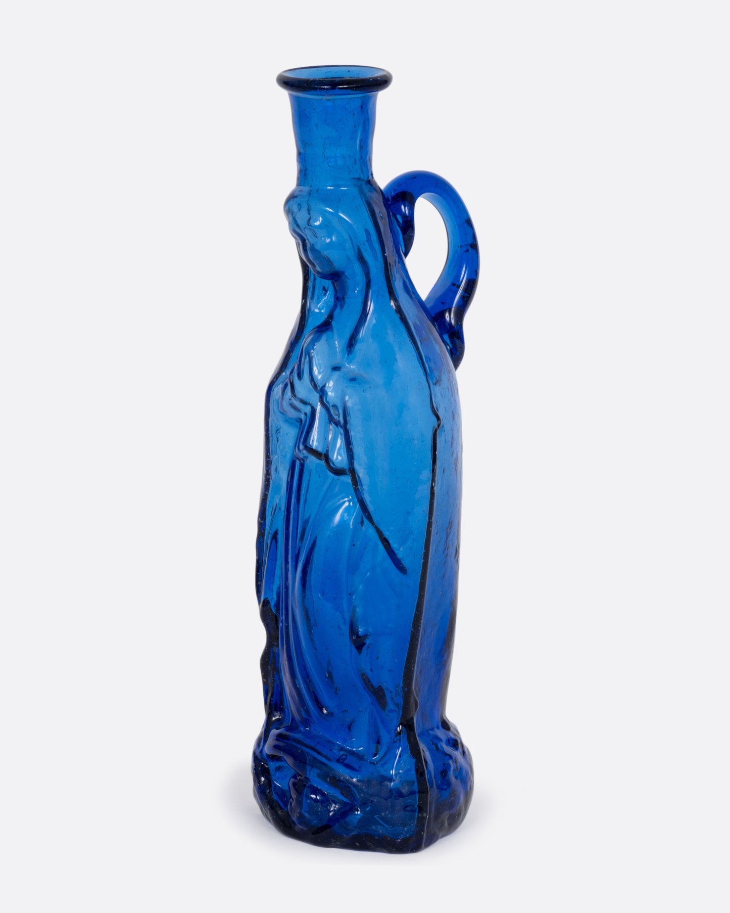 A blue glass vase with a praying Madonna and handle. Shown from the side.