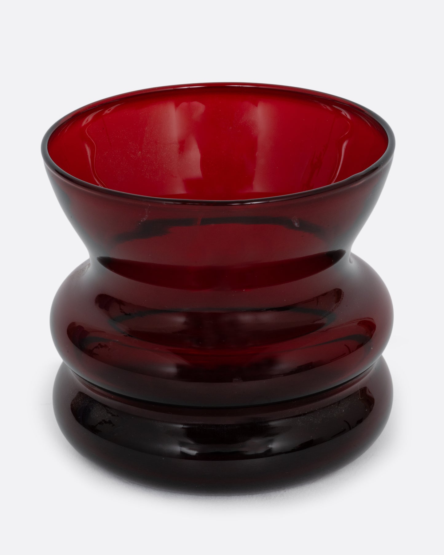 A short red glass vase with a wavy silhouette. Shown from the front.