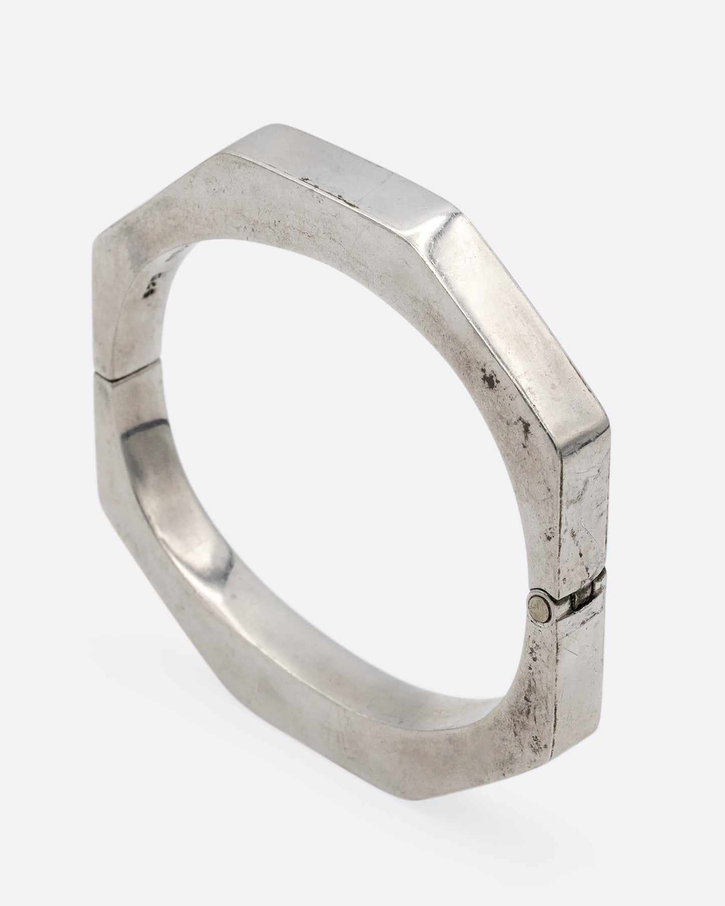 A silver octagonal bangle bracelet, shown standing up from the side.