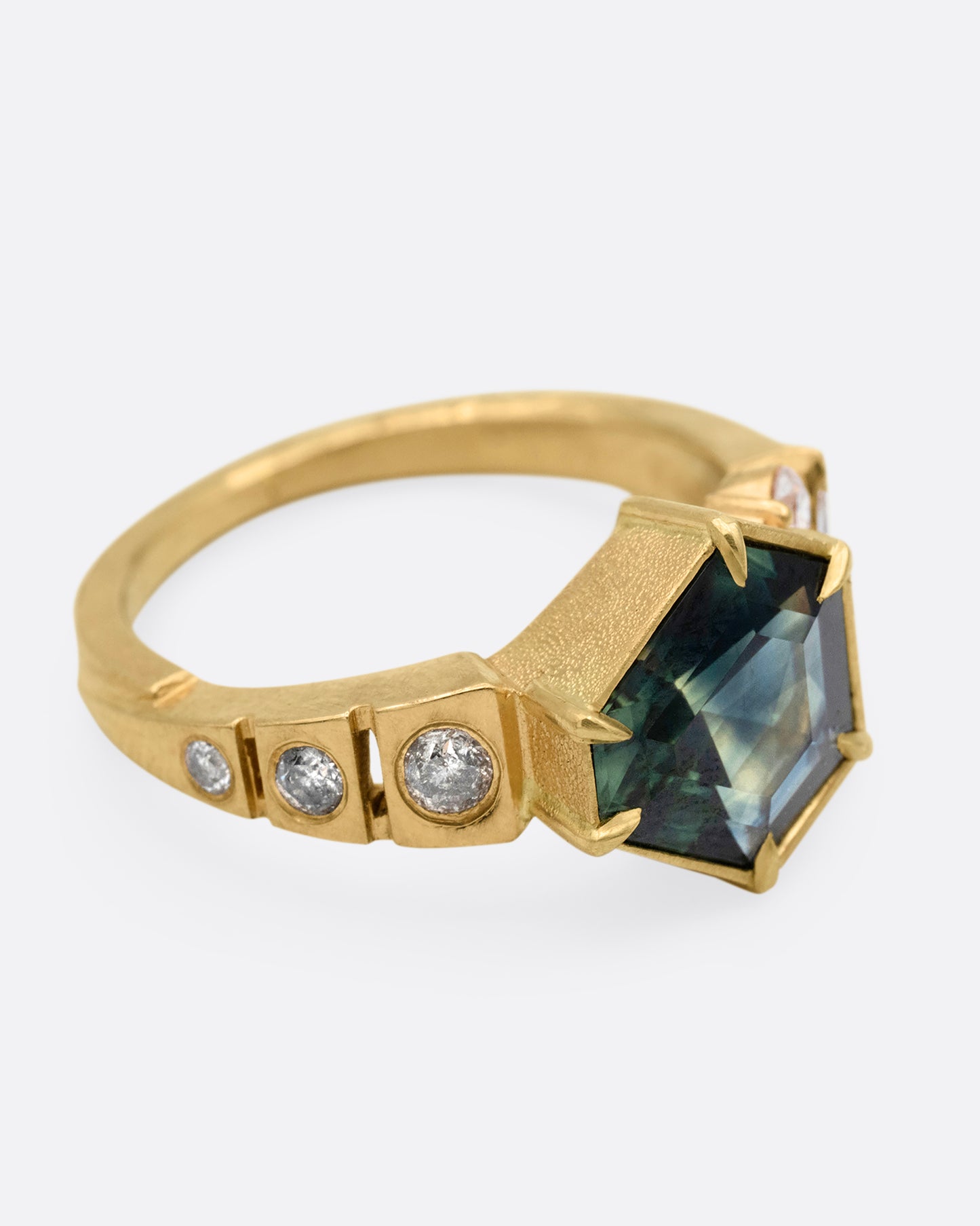 A yellow gold ring with a prong set Australian sapphire and white diamonds shown from the side.