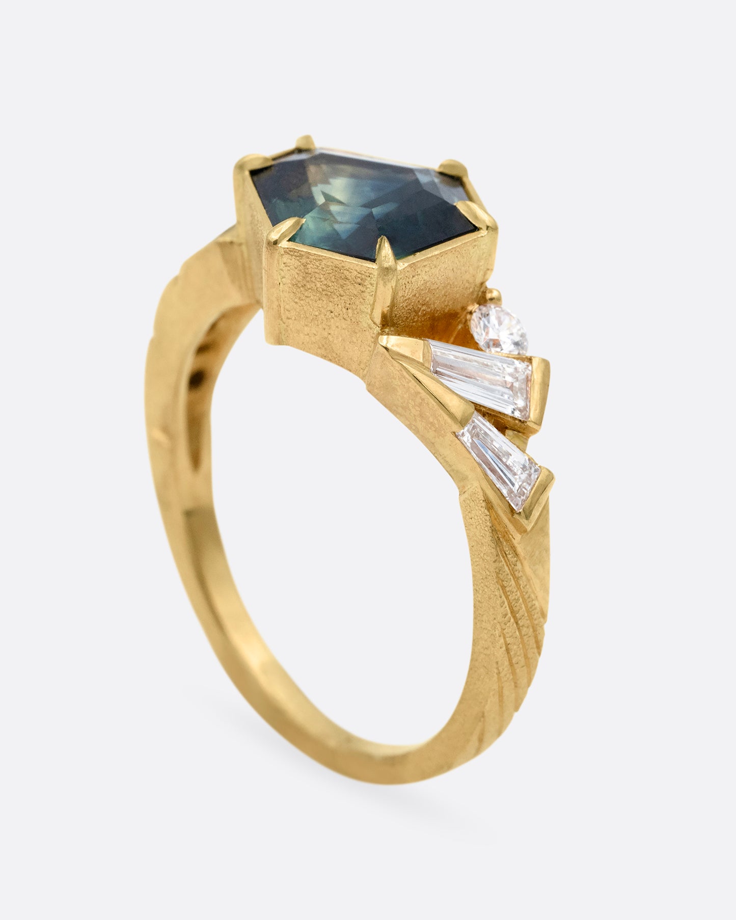 A yellow gold ring with a prong set Australian sapphire and white diamonds shown standing up from the side.