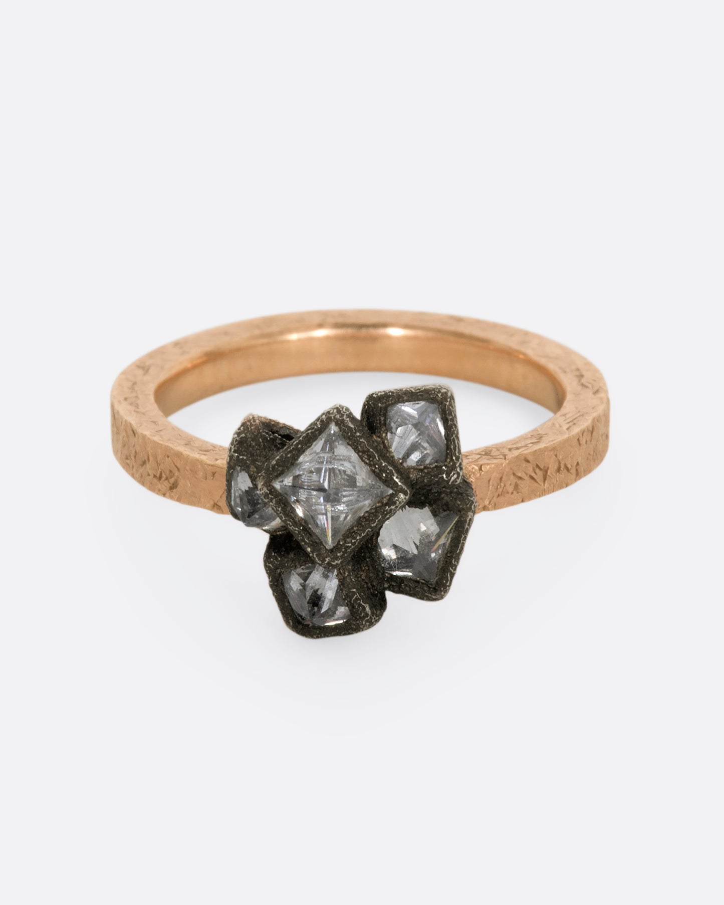 Inverted princess cut diamonds are piled high on top of a simple rose gold band. View from the front.
