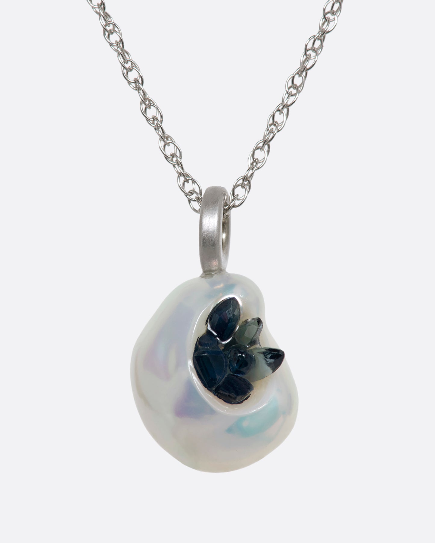 A white keshi pearl pendant filled with reclaimed sapphires hanging on a white gold chain. View from the front.