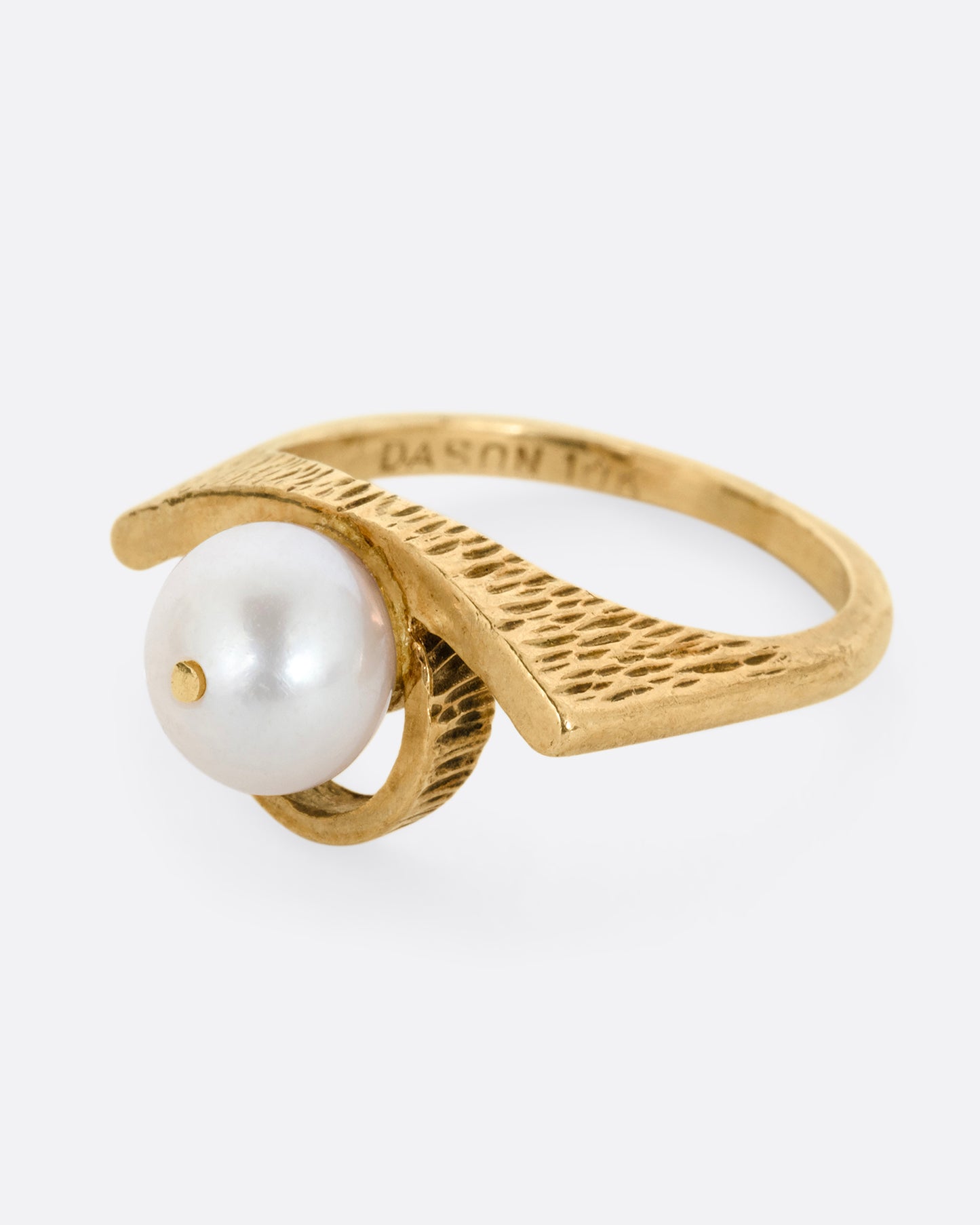 A yellow gold ring with a white pearl shown from the side.