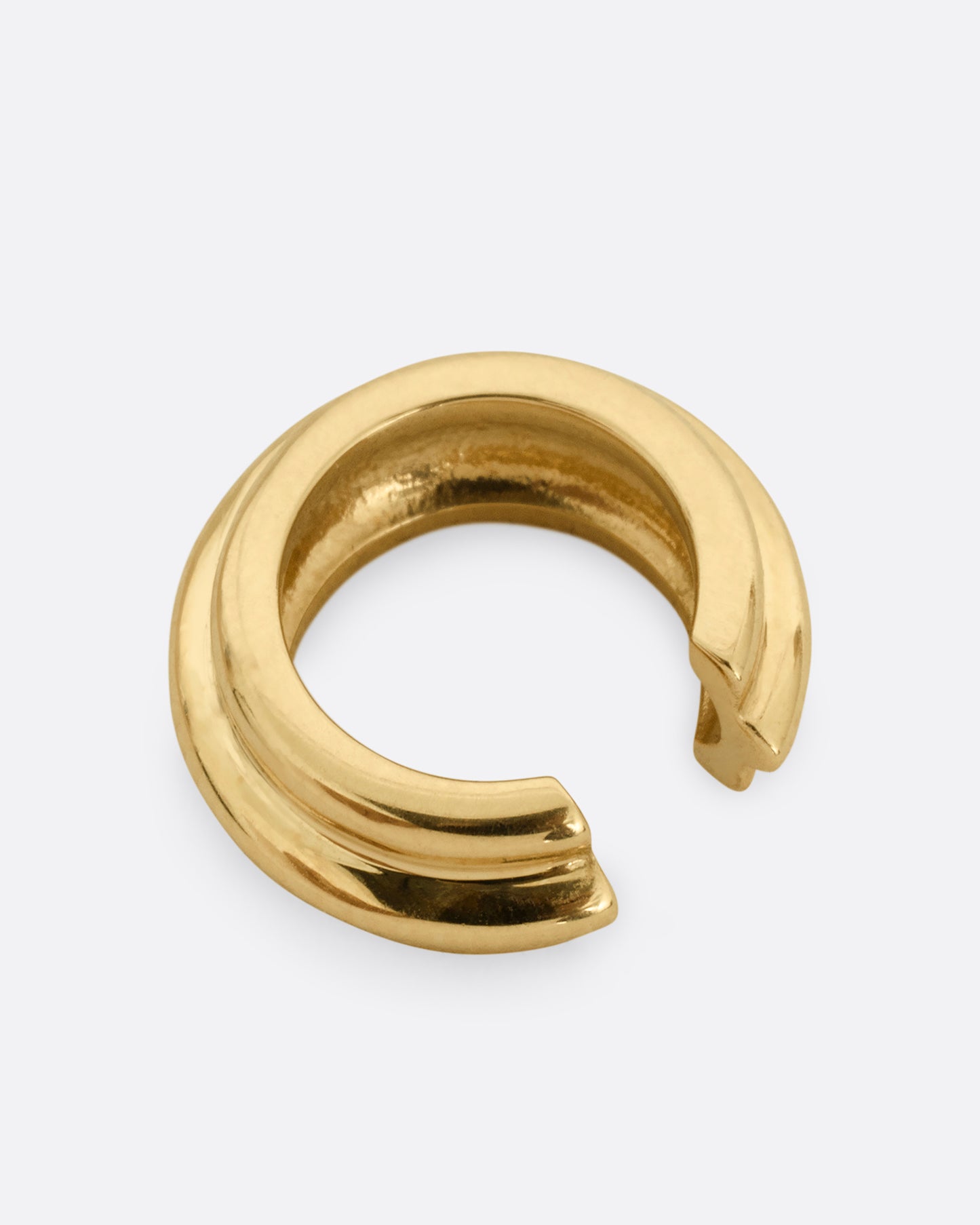 A yellow gold hoop shaped ear cuff shown from the back.