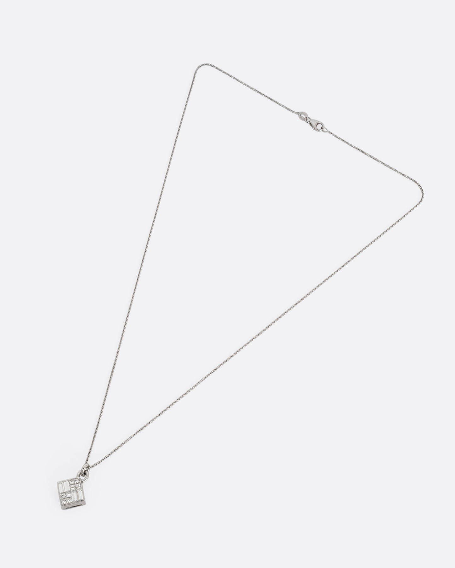 A white gold cable chain necklace with a pendant of princess cut and baguette diamonds. Shown from the front.