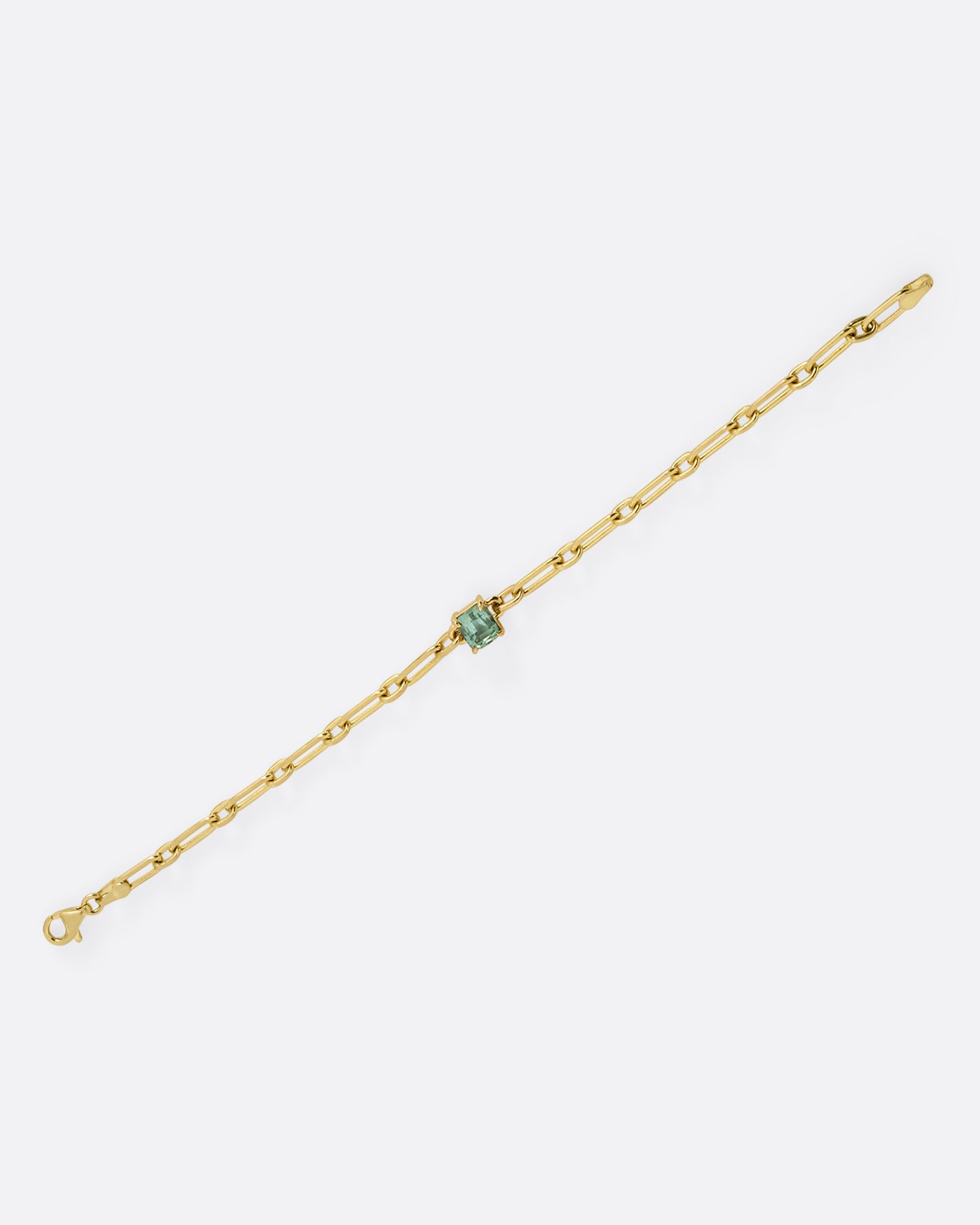 A yellow gold chain link bracelet with a prong set aqua tourmaline at the center. Shown from the front.