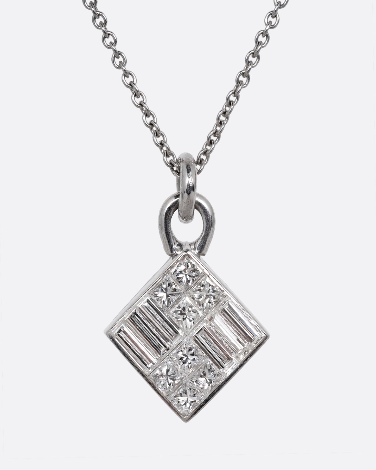 A white gold cable chain necklace with a pendant of princess cut and baguette diamonds. Shown from the front.