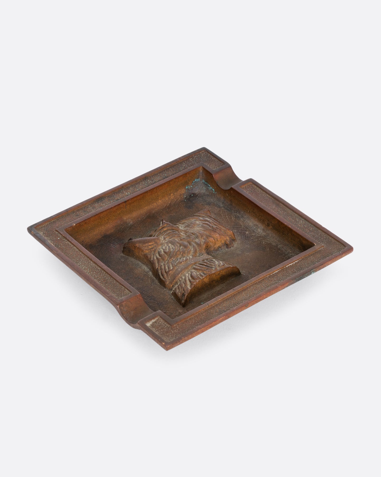 A square brass ashtray with a dunhill Scottie and a cork bottom. Shown from the top at an angle.