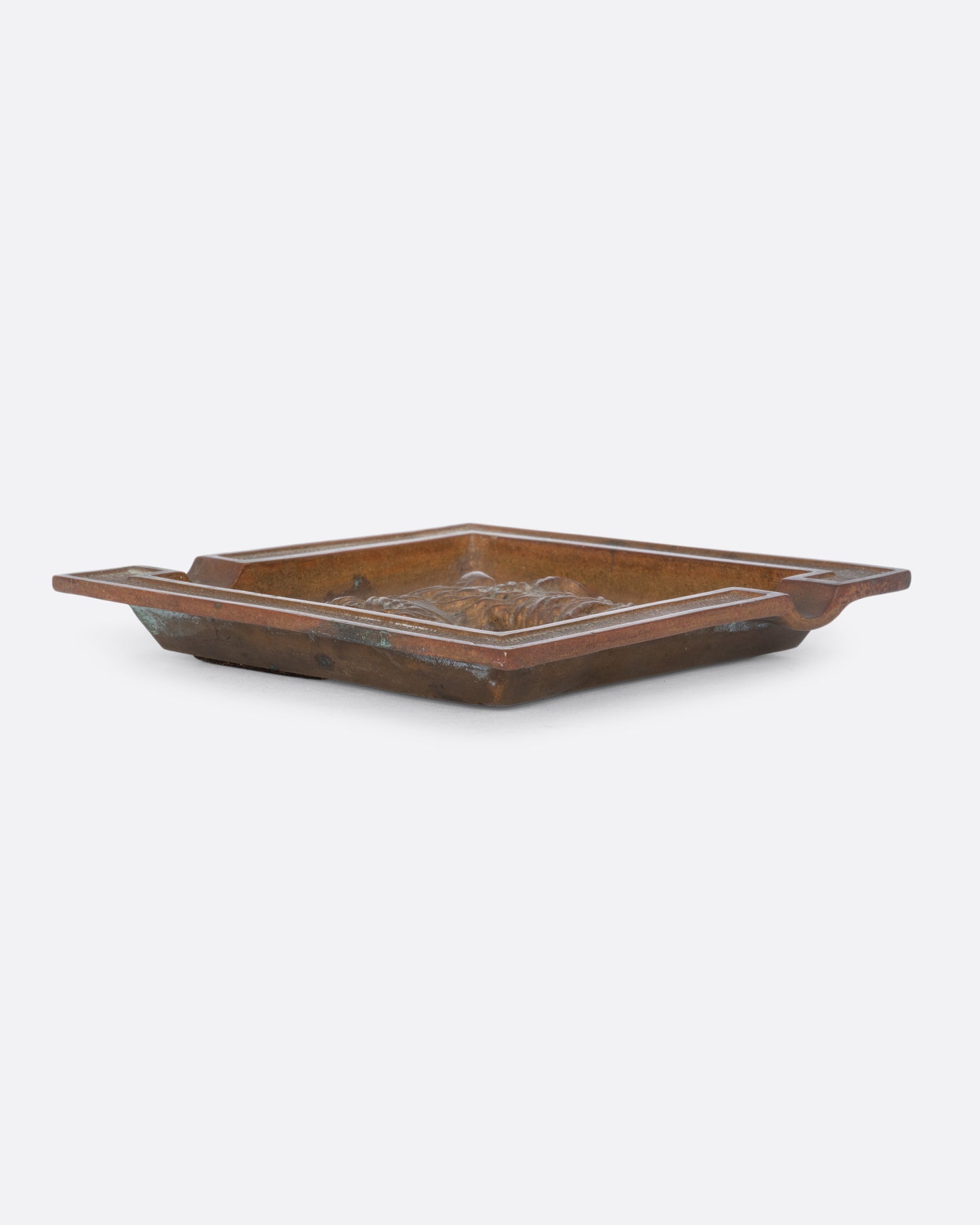 A square brass ashtray with a dunhill Scottie and a cork bottom. Shown from the side.