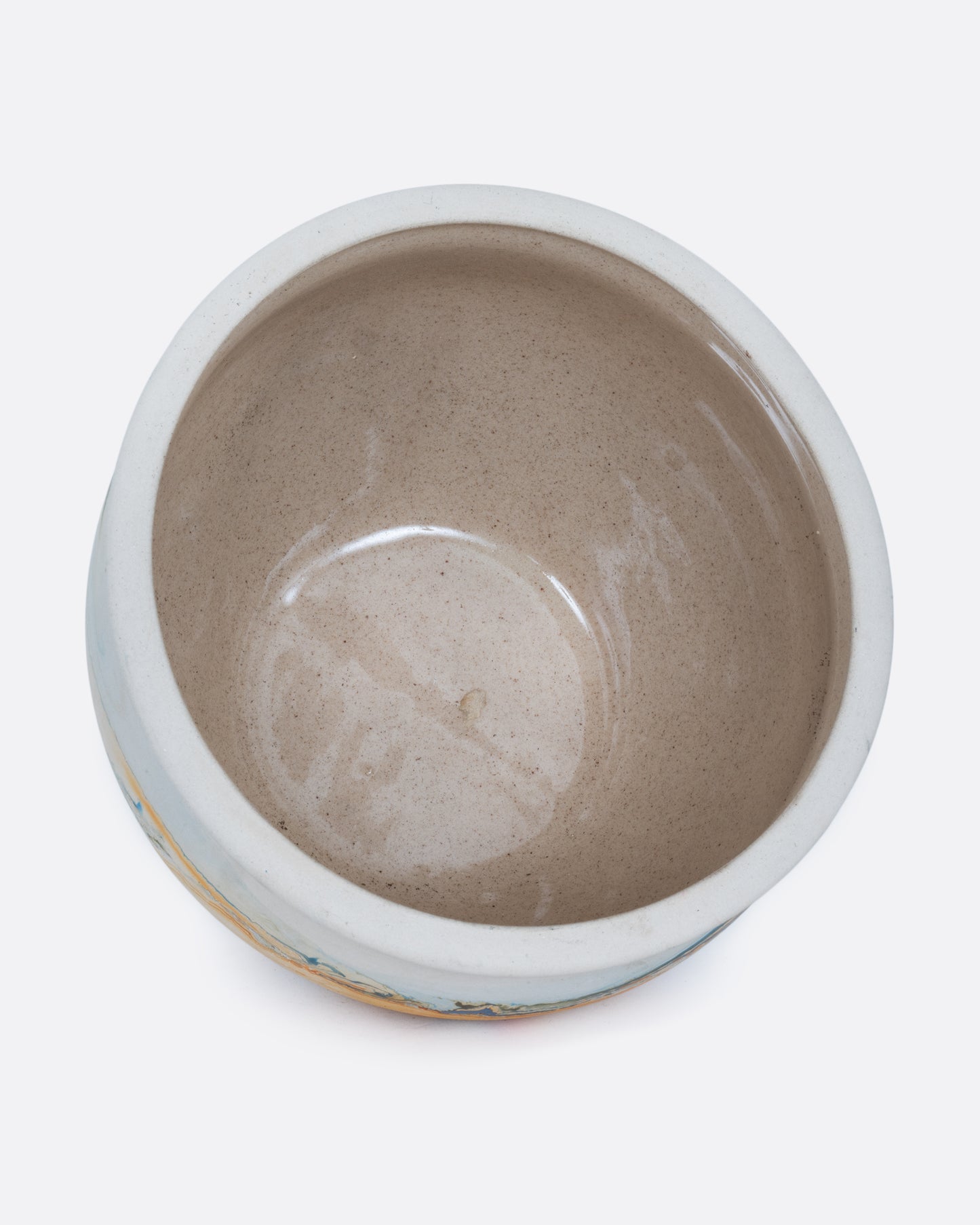 A white Nemadji pot with swirls of blues and golds shown from the top.