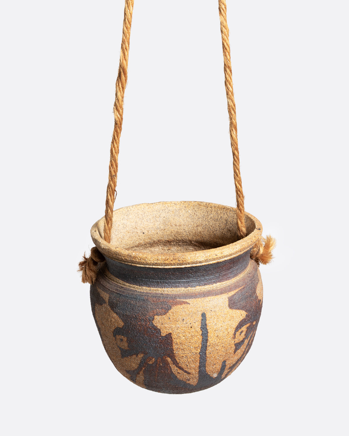 A ceramic pot with an abstract tan and brown pattern and cords for hanging, shown from the front.