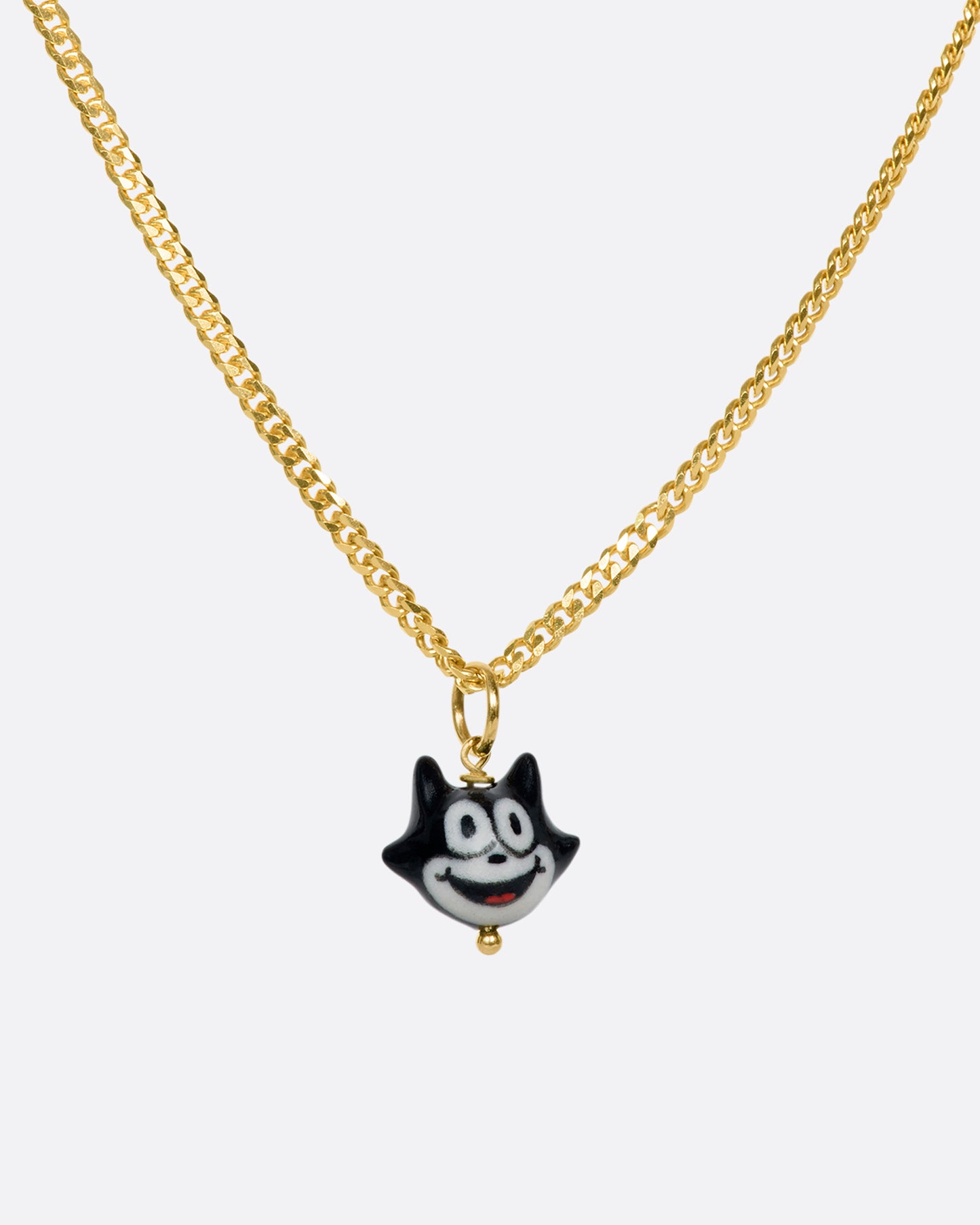 A handmade and painted porcelain Felix the Cat charm with a 14k gold bail