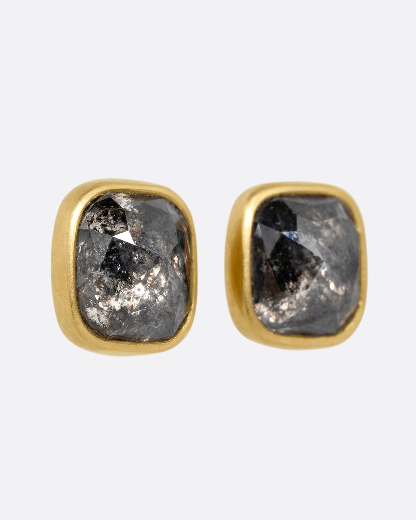 A pair of yellow gold square salt and pepper stud earrings, shown from the side.