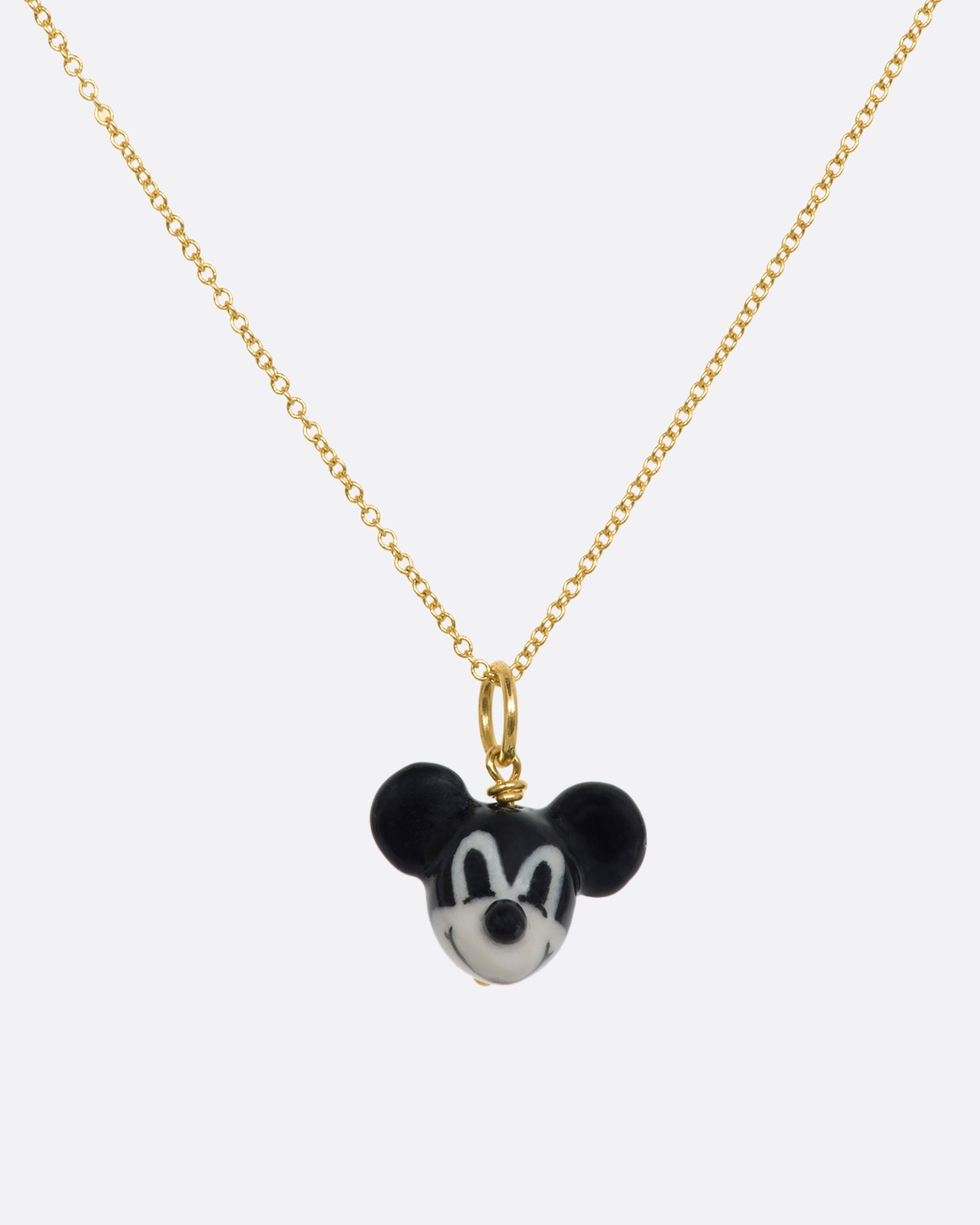 A three dimensional black and white era mickey mouse charm with a yellow gold bail. Hanging from a yellow gold chain.