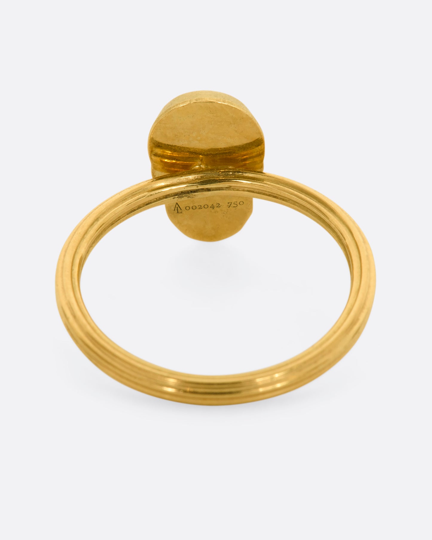 Back view of yellow gold ring with a sculpted skull charm on a round fluted band.