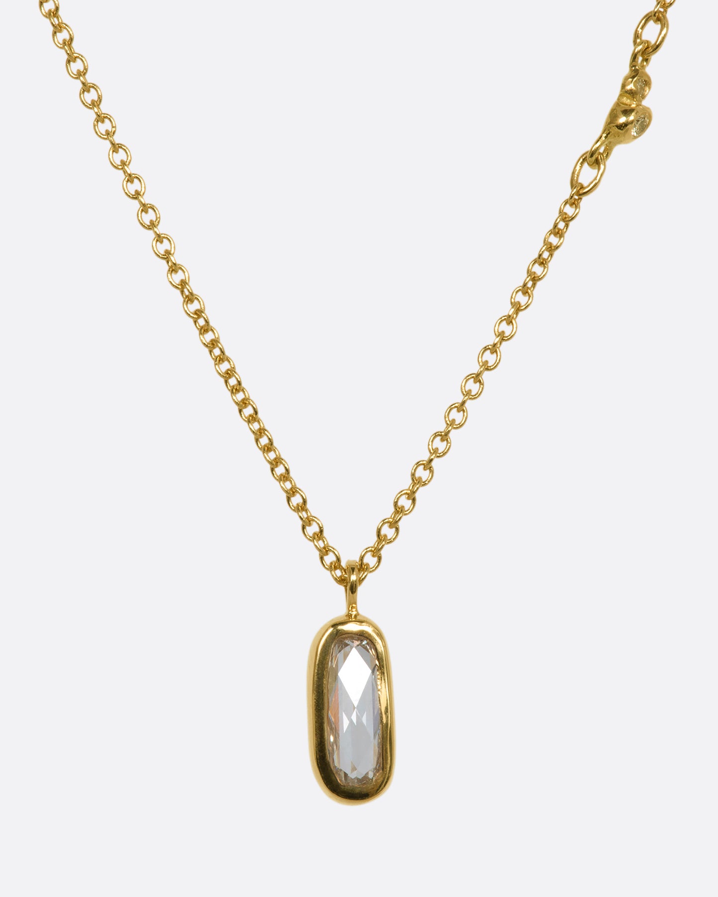 A yellow gold necklace with a rose cut solitaire diamond pendant and a cluster of diamonds on the chain. View from the front.