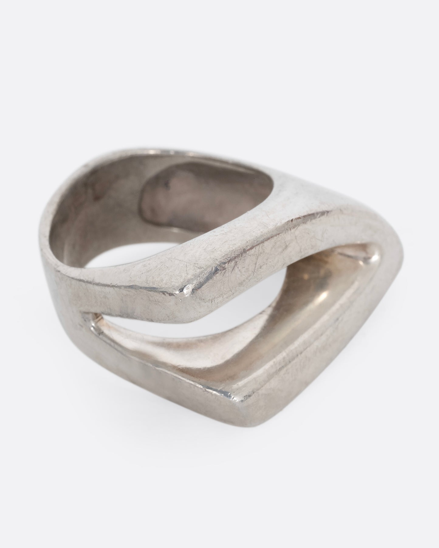 A silver ring with an angular cutout, shown from the side.