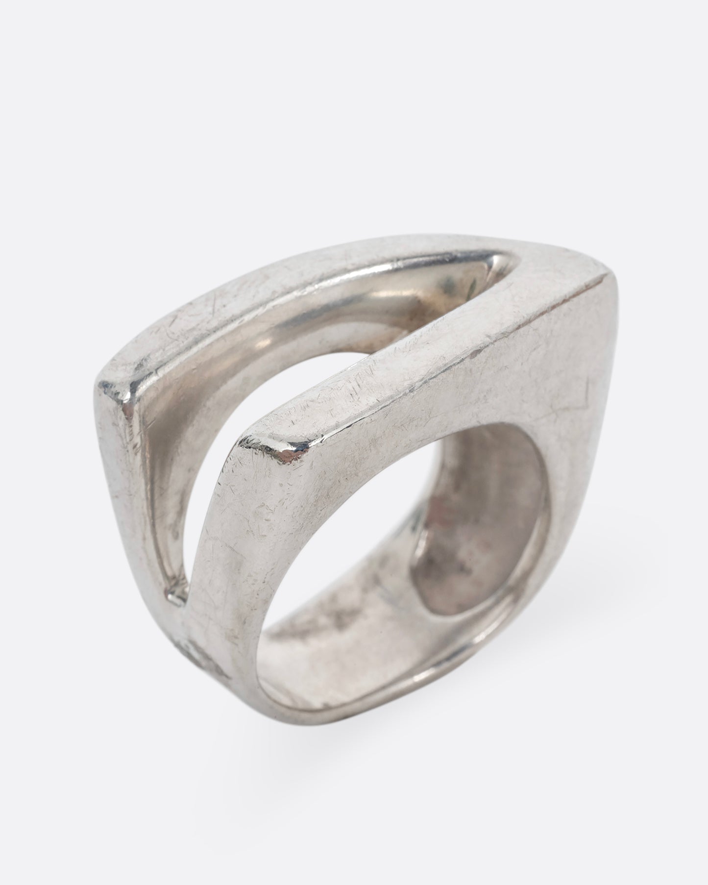 A silver ring with an angular cutout, shown standing up from the side.