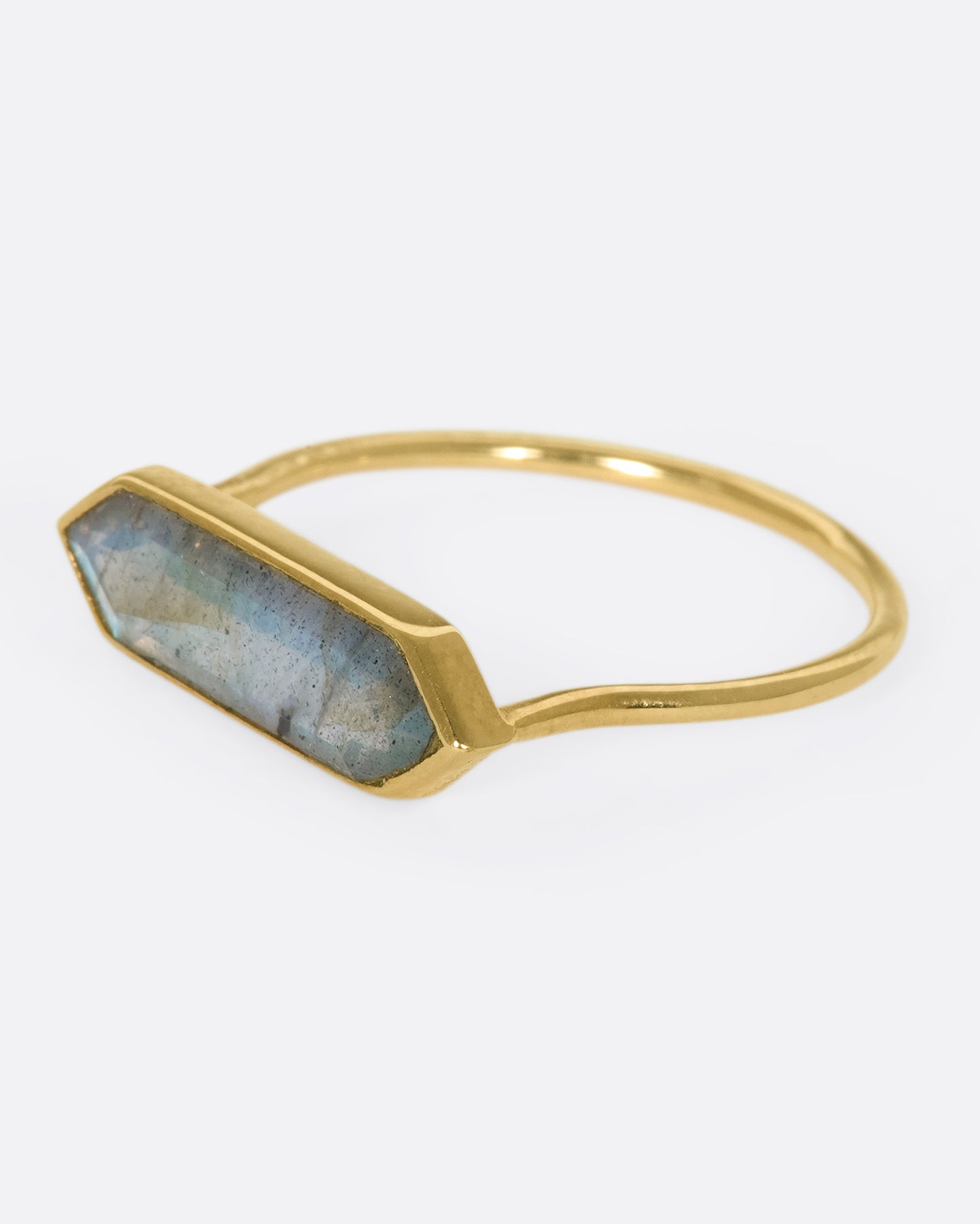 A yellow gold ring with a hexagonal labradorite bar, shown from the side.