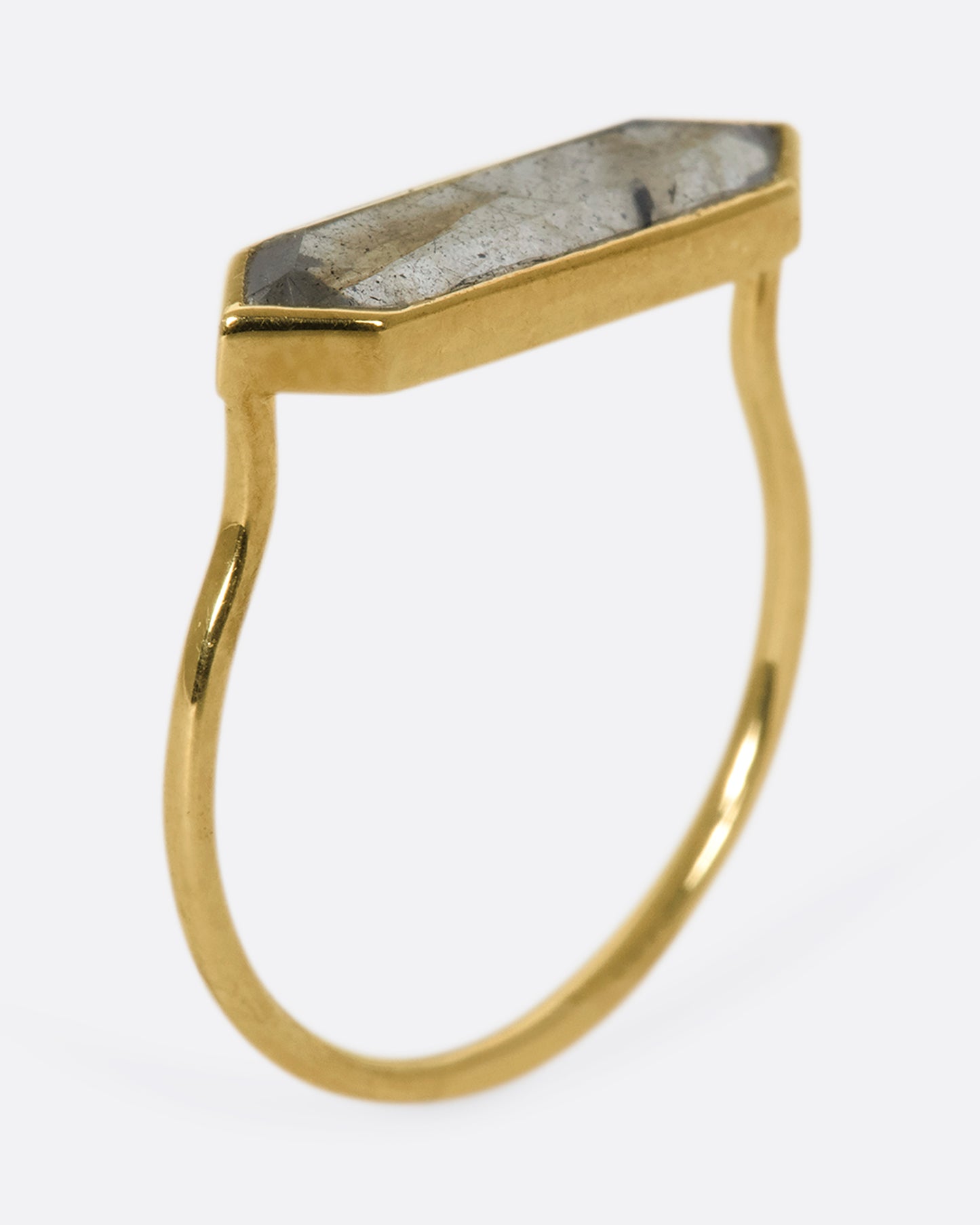 A yellow gold ring with a hexagonal labradorite bar, shown from the side, standing up.