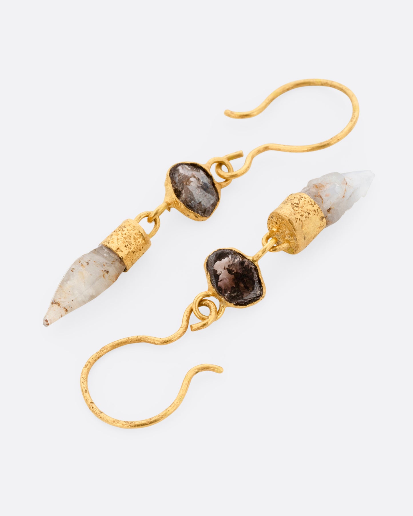 A pair of yellow gold drop earrings with Borneo diamonds and Sri Lanken sapphires, shown lying flat.