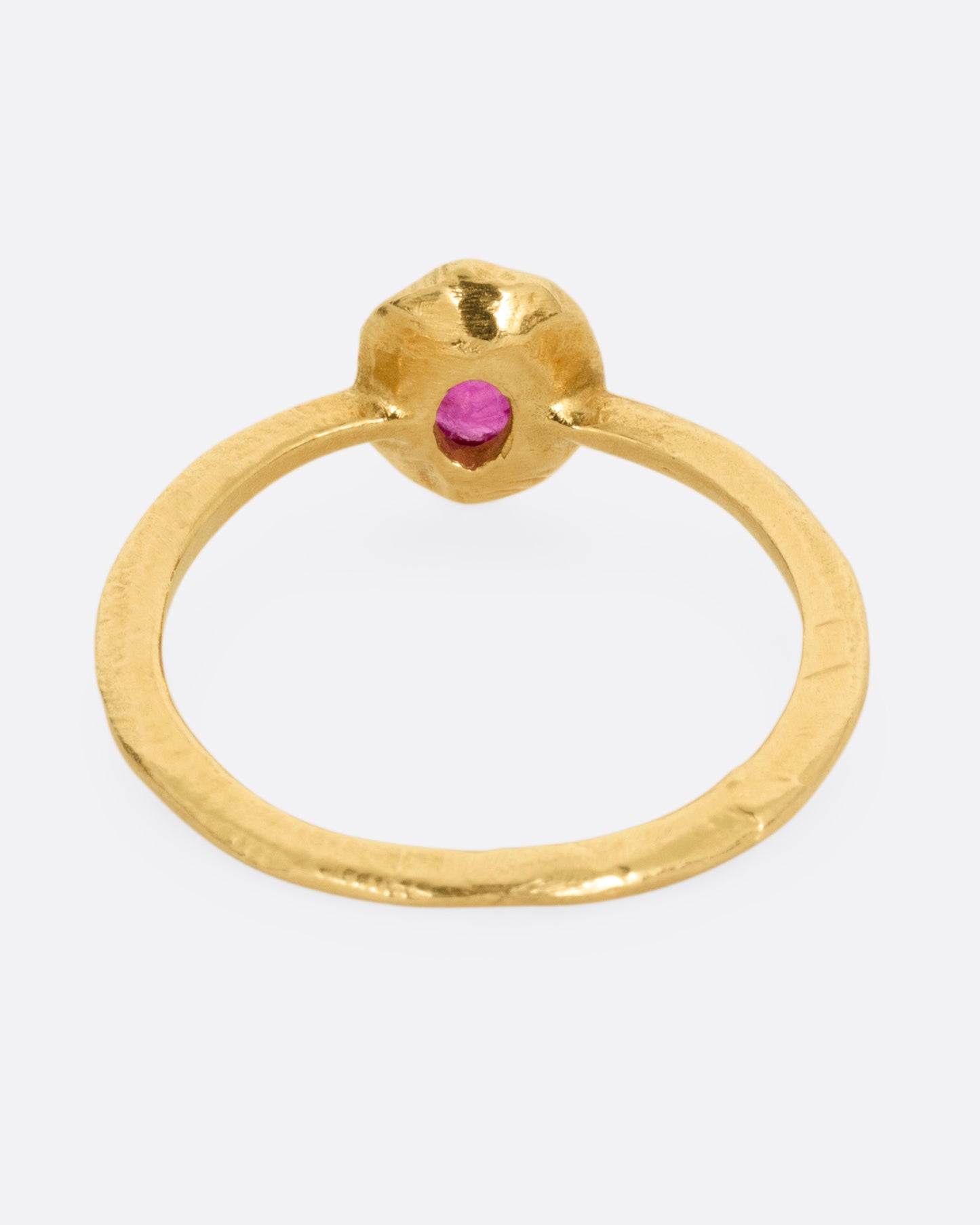 A yellow gold ring with a bezel set ruby, shown from the back.