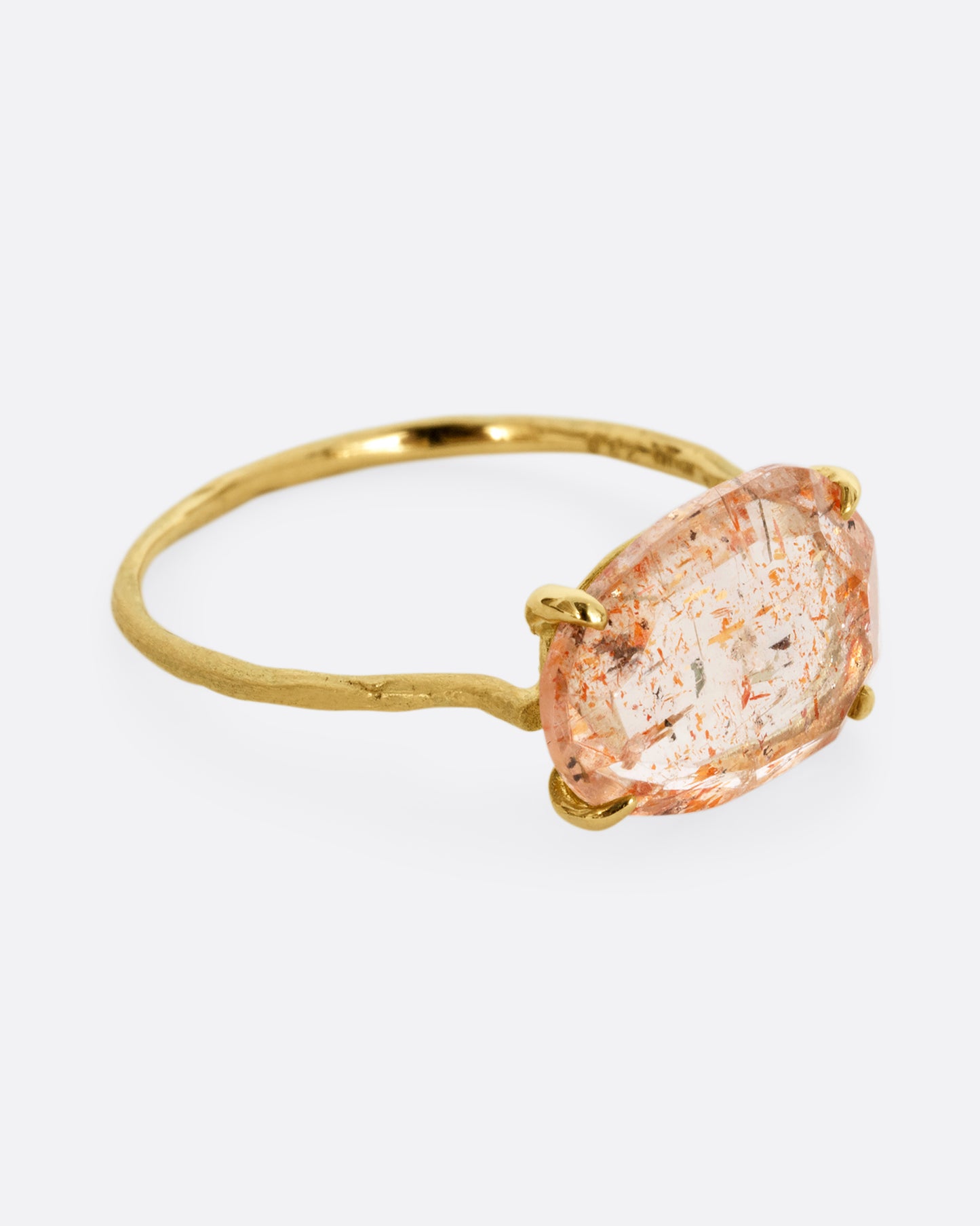 A yellow gold ring with a prong set sunstone. Shown from the side.