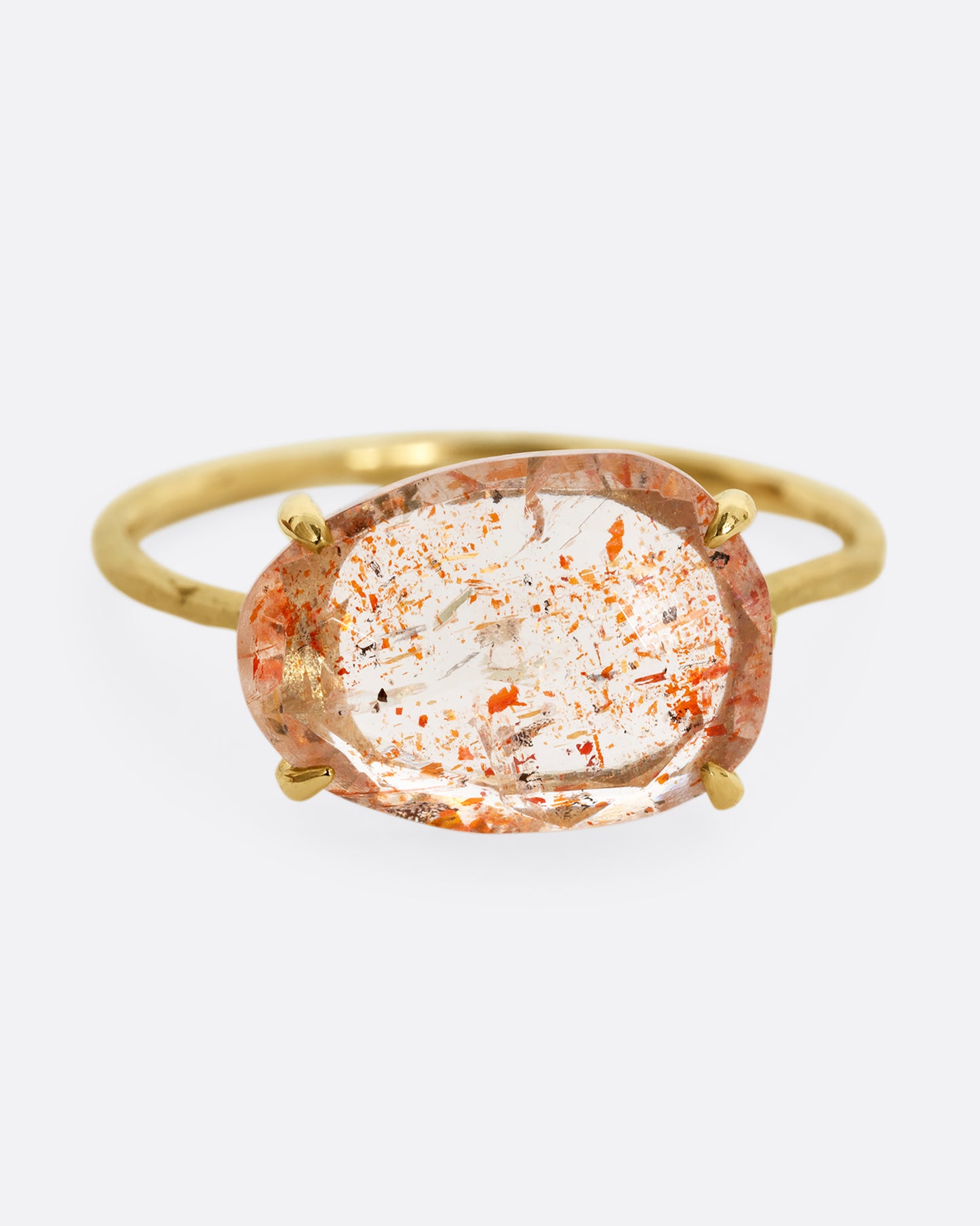A yellow gold ring with a prong set sunstone. Shown from the front.