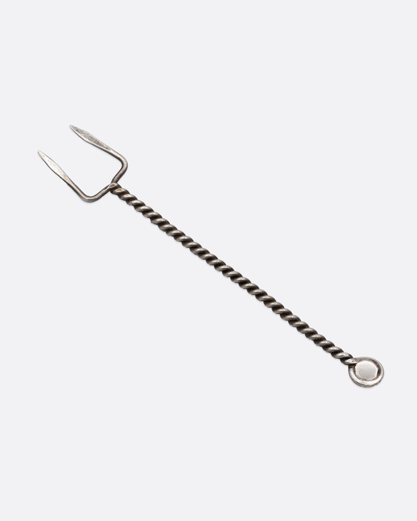 A two pronged silver olive pick with a twisted handle and round turquoise stone at the bottom. Shown from the back.