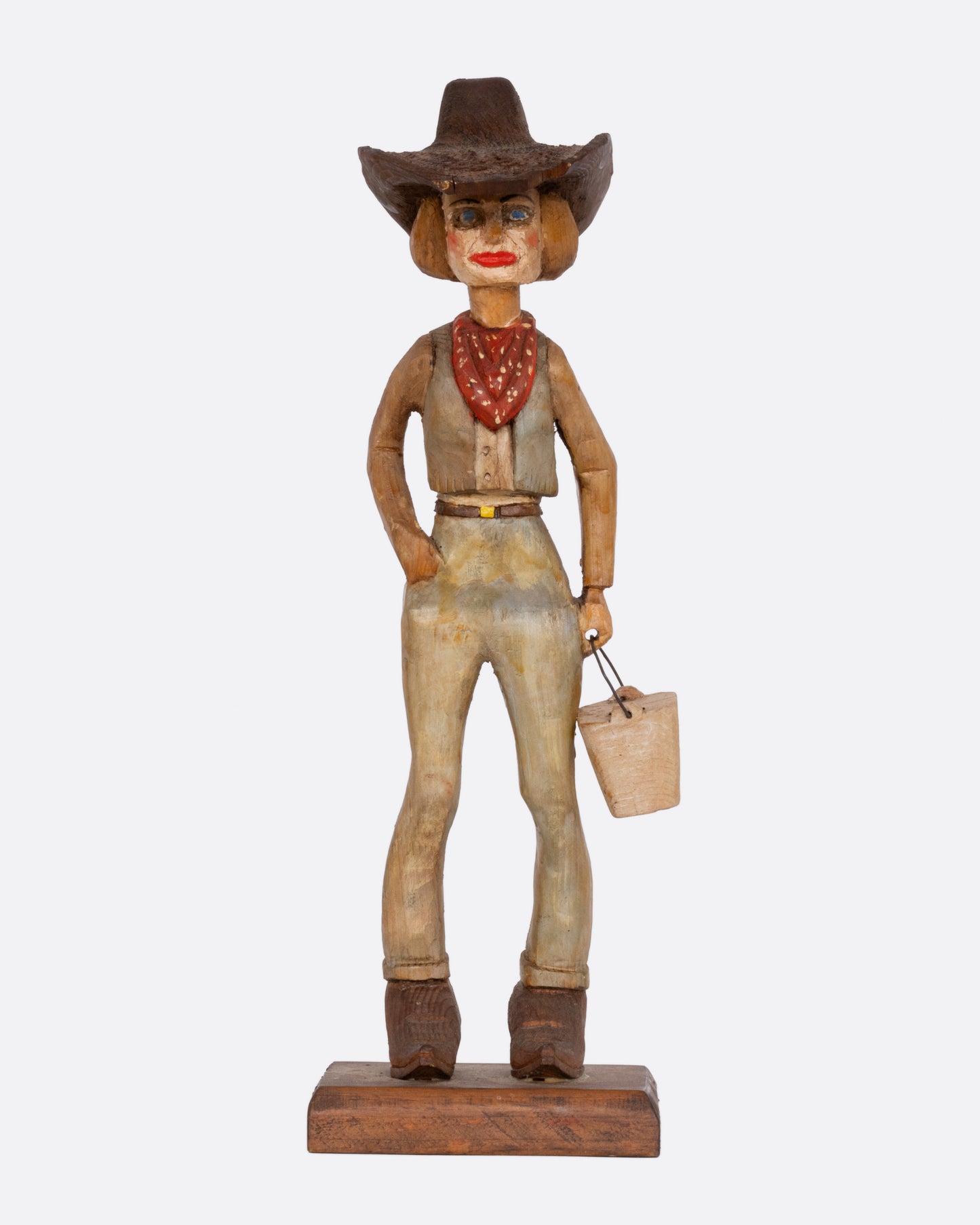 A wooden hand carved and painted folk art cowgirl holding a bucket. Shown from the front.