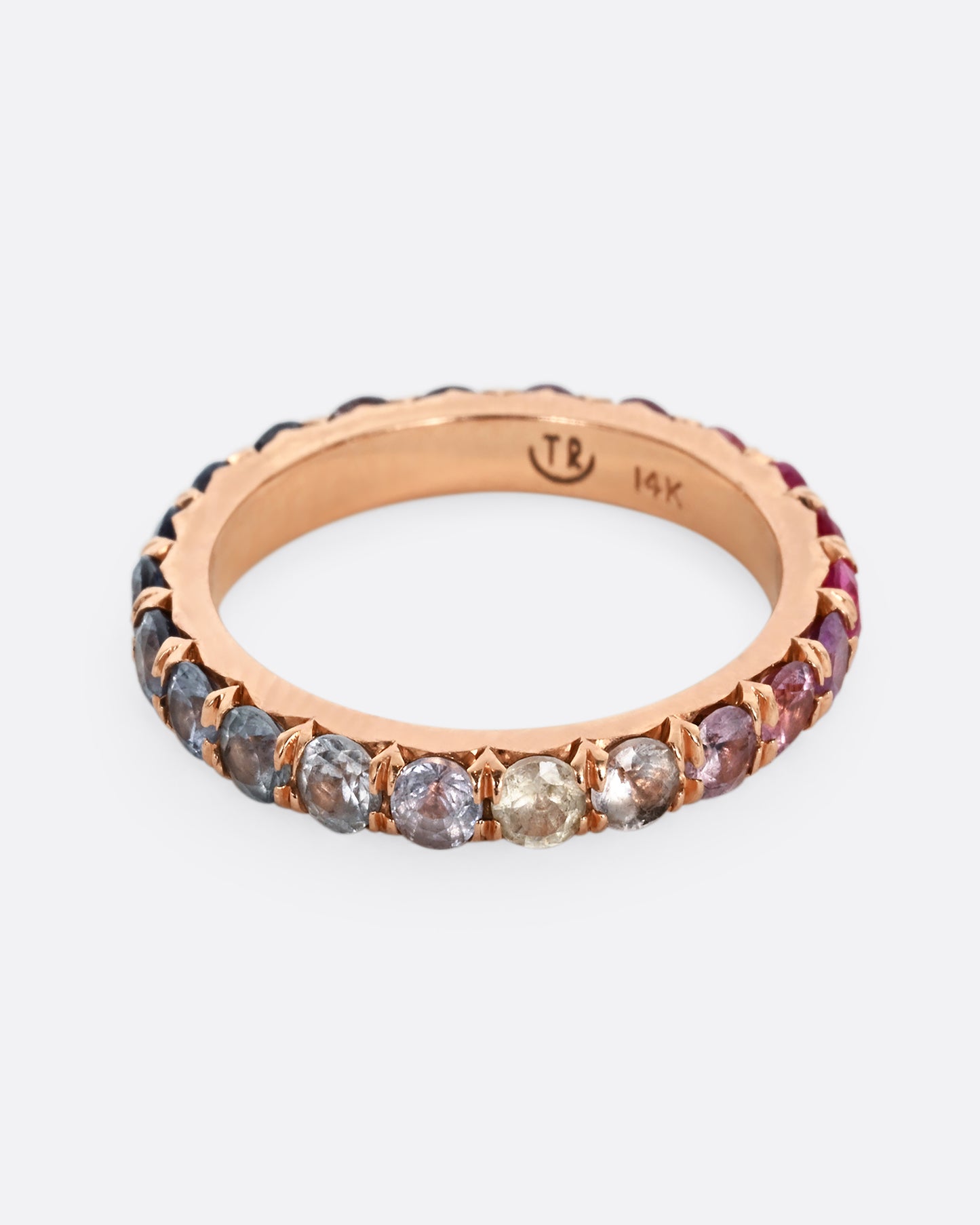 A rose gold eternity band with pink and blue cut sapphires.