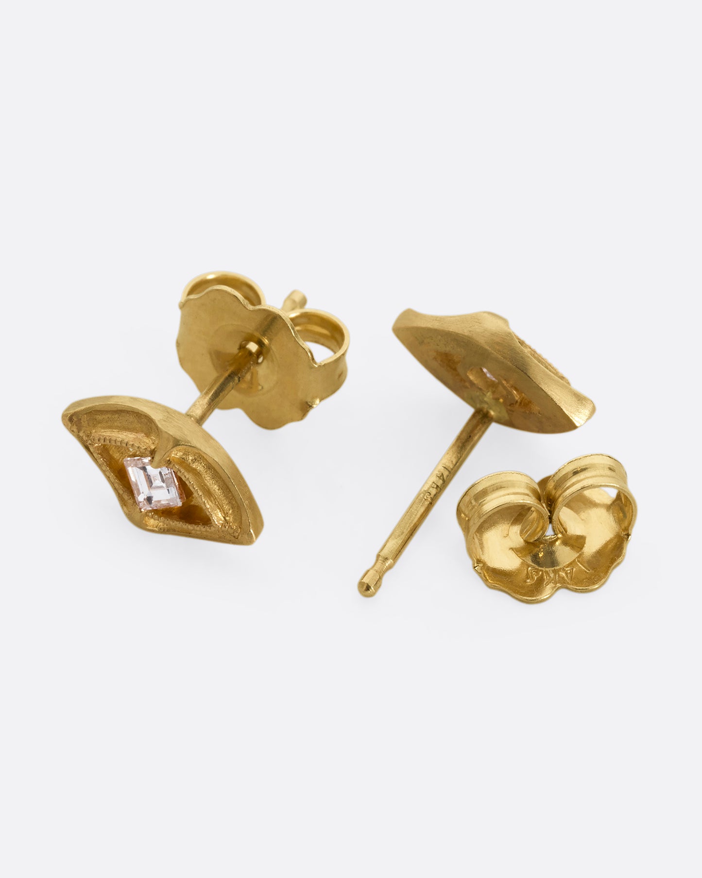 A pair of yellow gold earrings shaped like an eye with a diamond at the center. Shown from the front and back alternating.