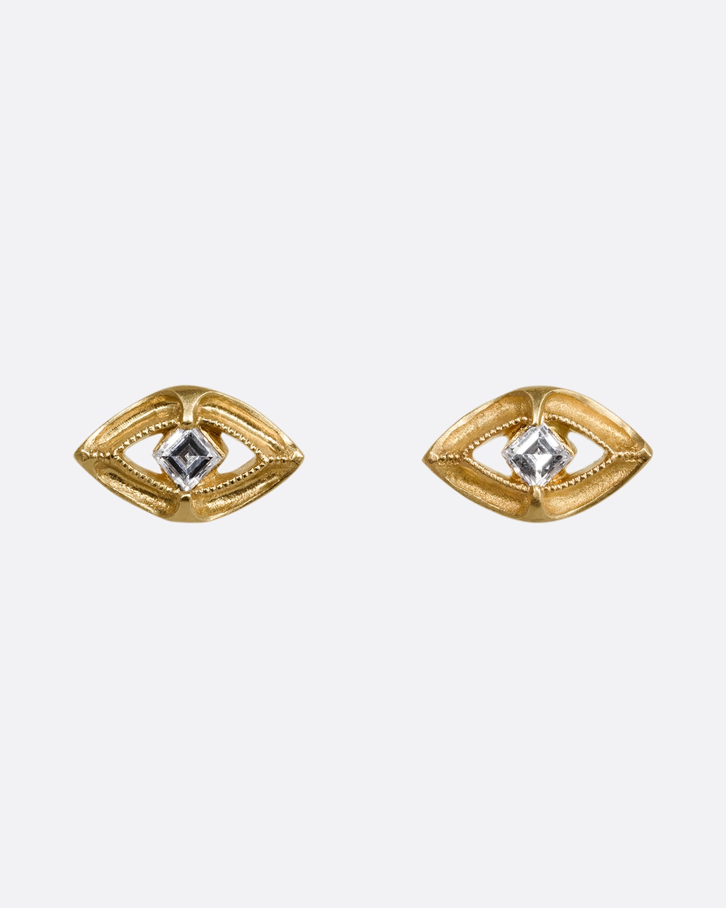 A pair of yellow gold earrings shaped like an eye with a diamond at the center. Shown from the front.