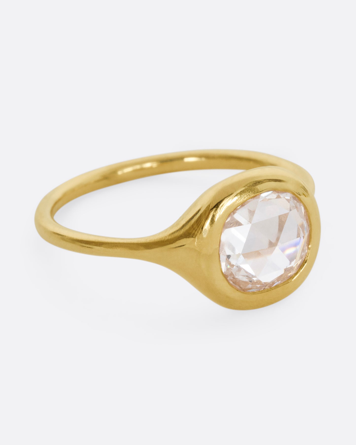 A yellow gold hand carved ring with a brilliant rose cut diamond. Shown from the side.