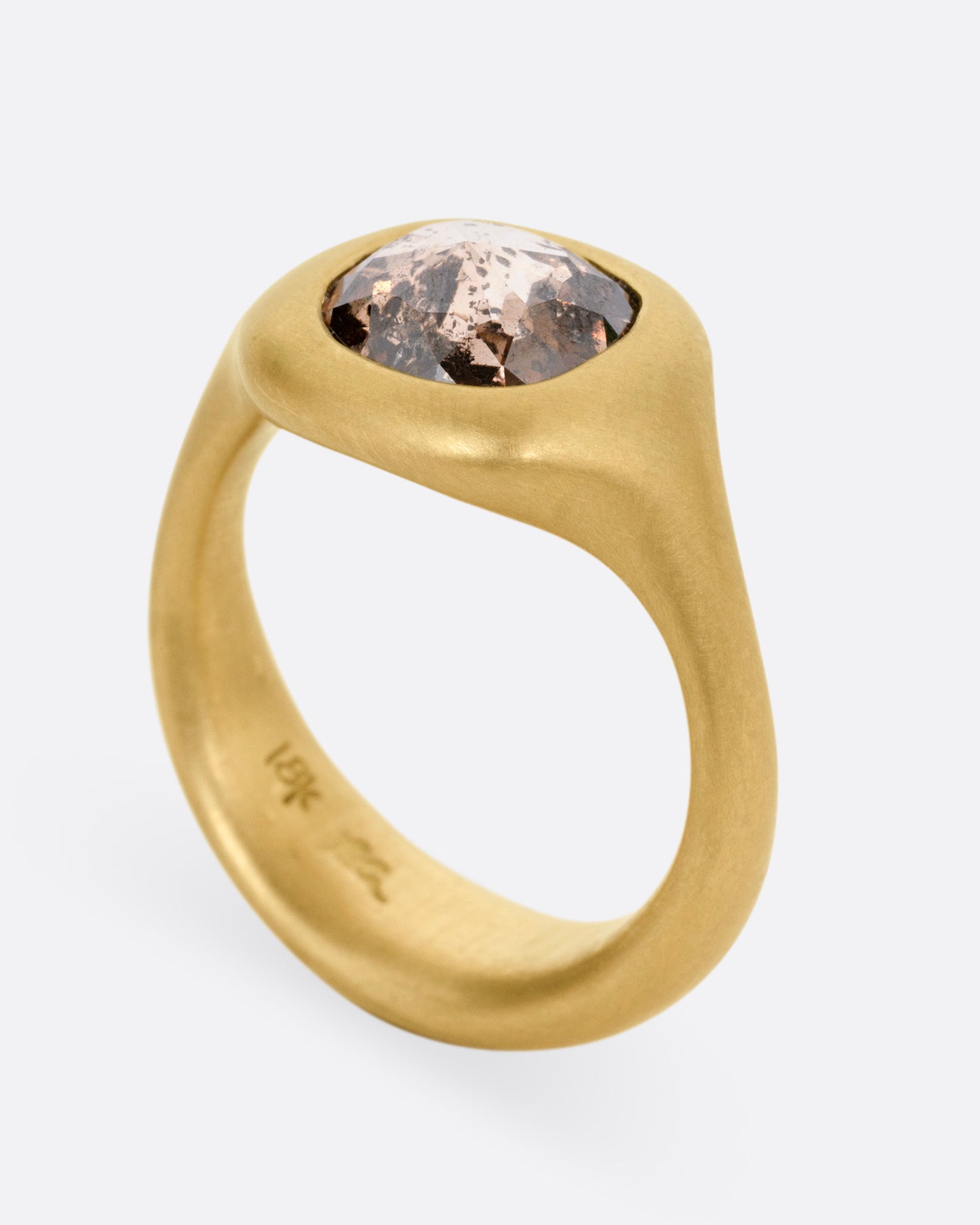 A yellow gold ring with a cognac diamond, shown from the side standing up.