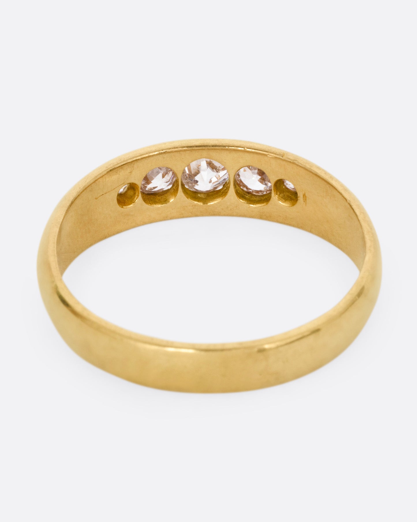 A yellow gold ring with five Old European cut diamonds, shown from the back.