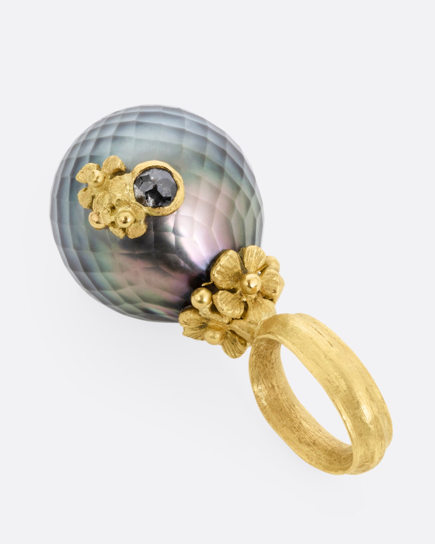 A yellow gold textured Tahitian pearl pendant with diamond accented flowers. Shown from the side.