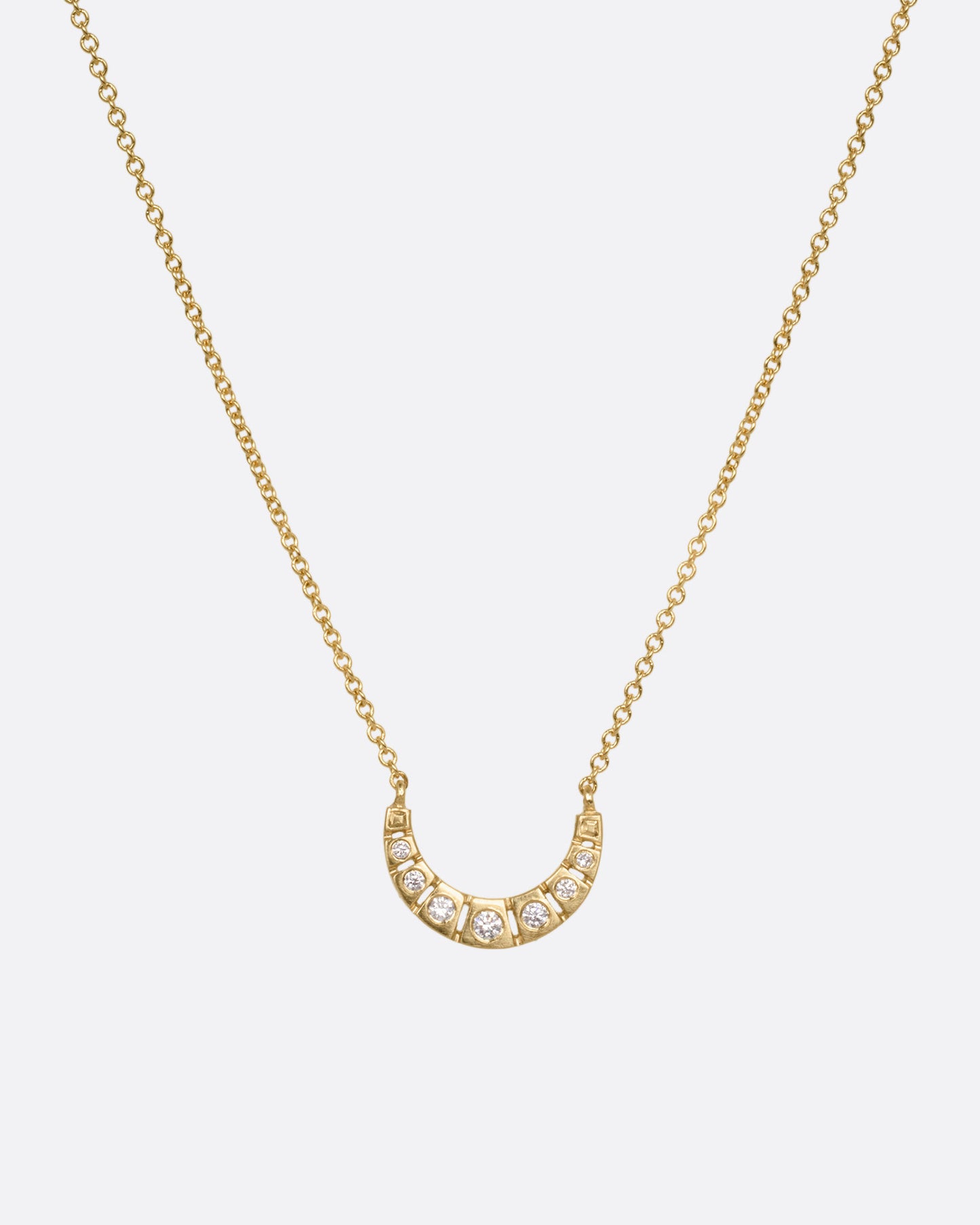 A yellow gold necklace with a crescent moon studded with brilliant cut diamonds, shown from the front.