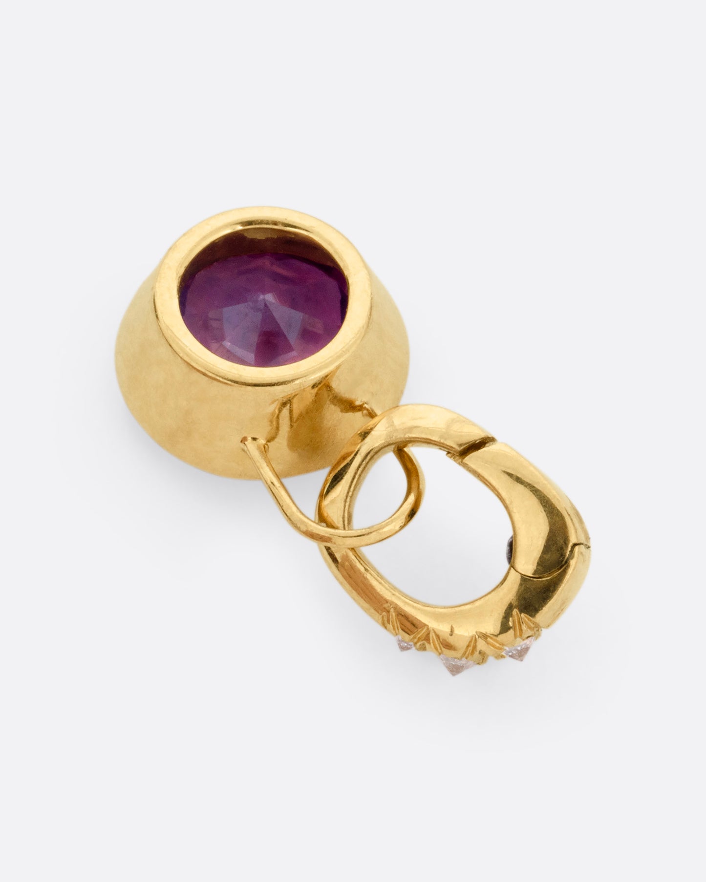 A yellow gold pendant with a pink sapphire and a diamond studded clip lock bail, shown from the back.
