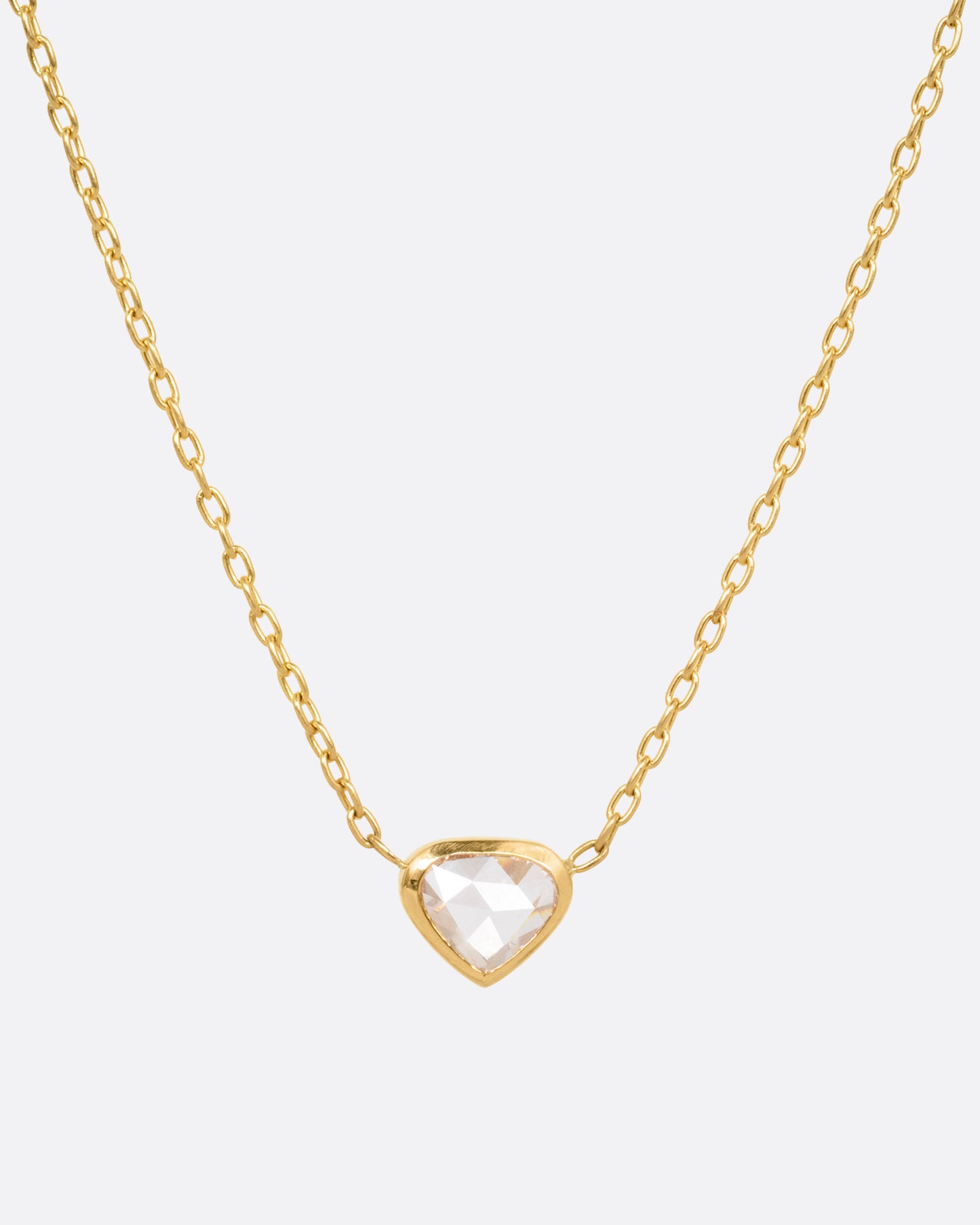 A yellow gold necklace with a natural organic heart shaped diamond, shown from the front.