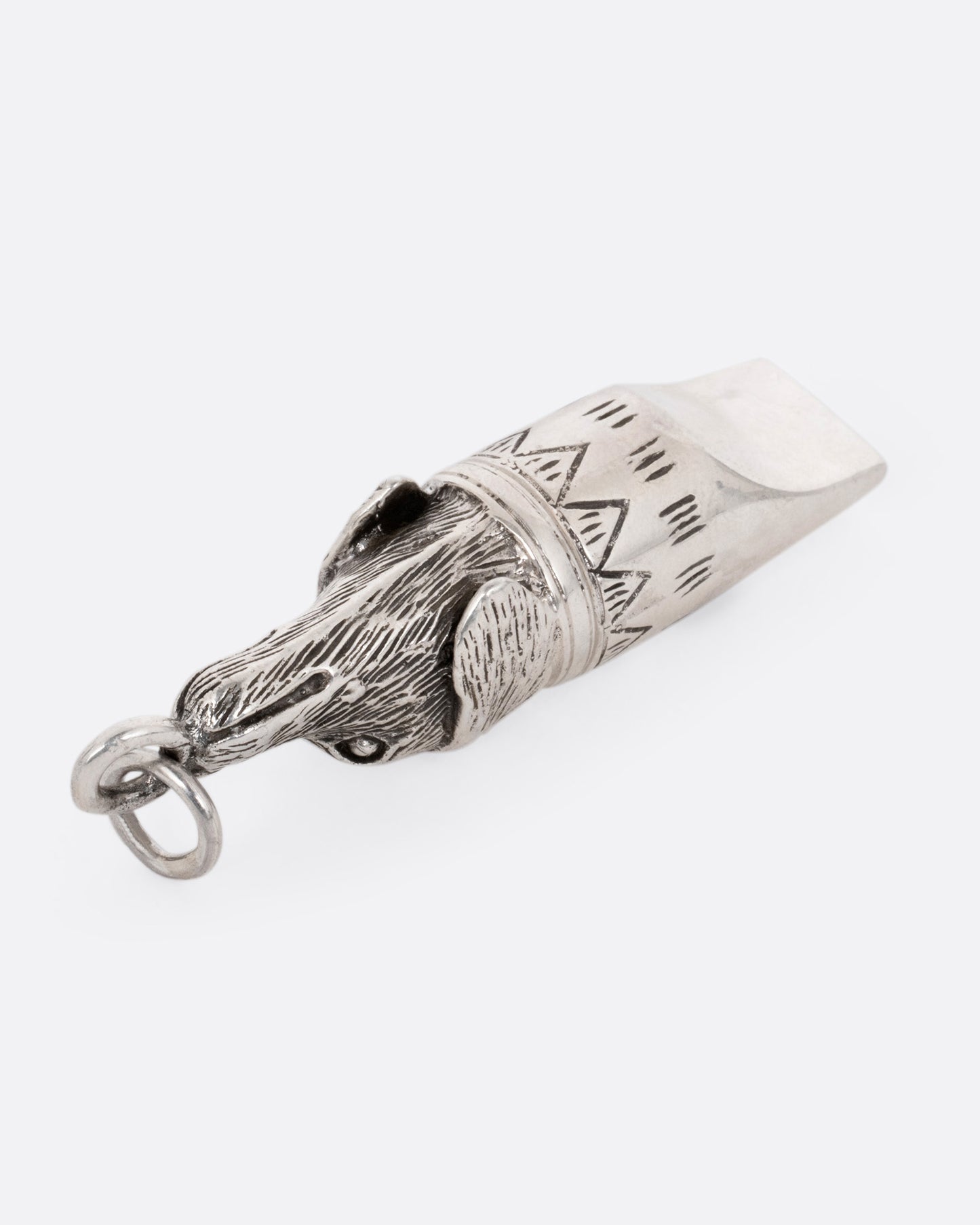 A silver dog whistle with a dog head at one end. Shown from the bottom.