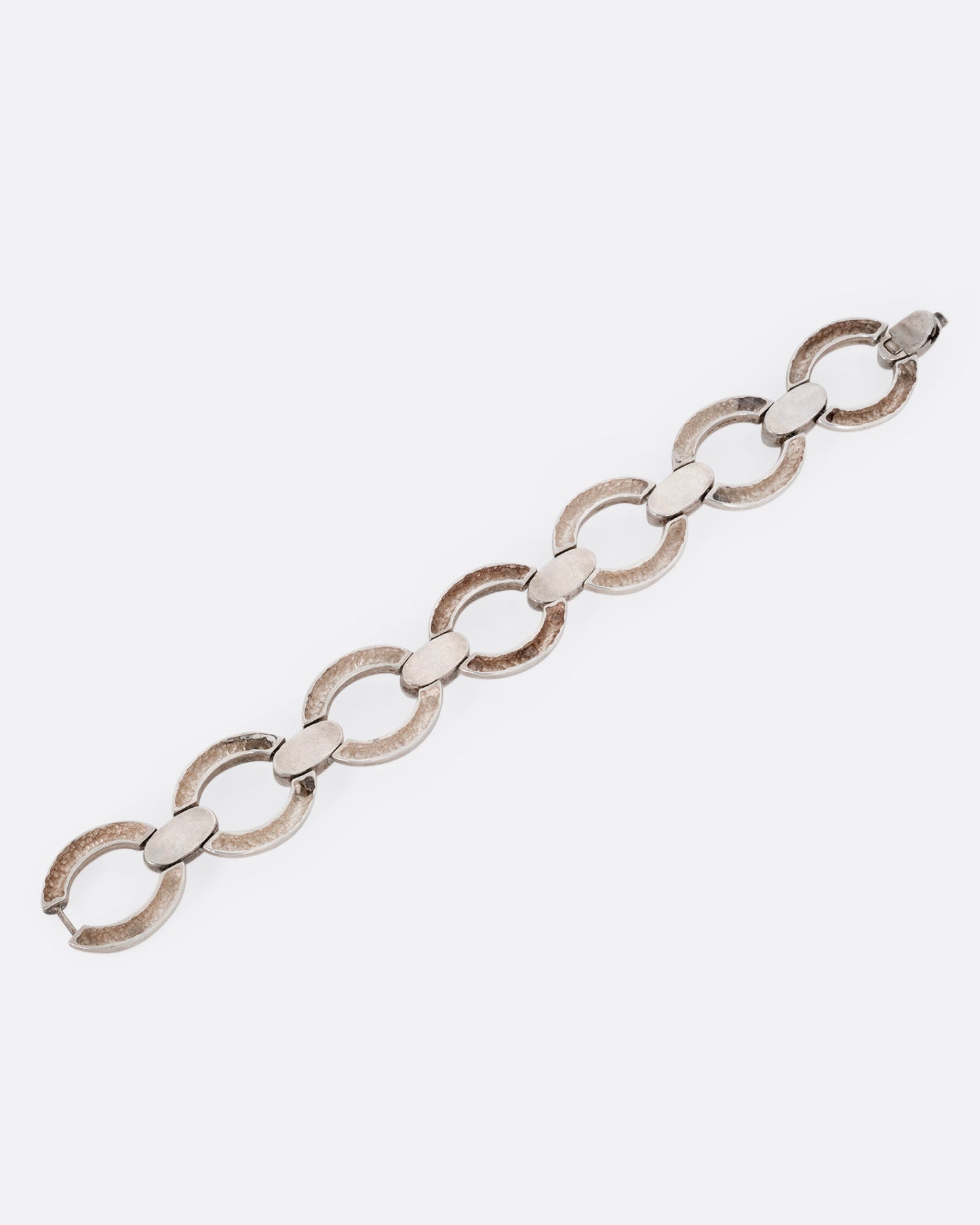 A silver bracelet with broad open oval links, shown from the back.